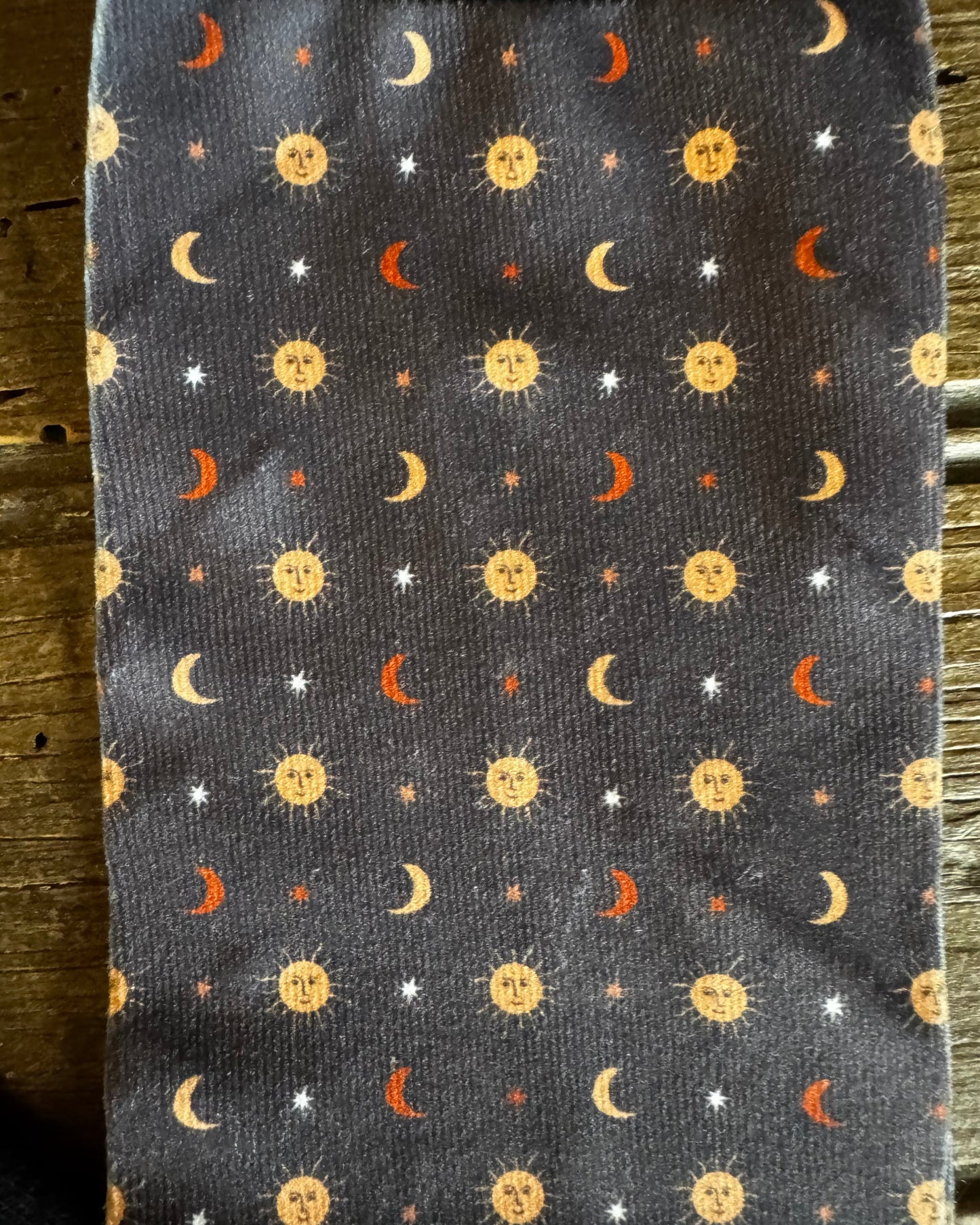 Socks with celestial pattern of suns, moons, and stars on a dark background