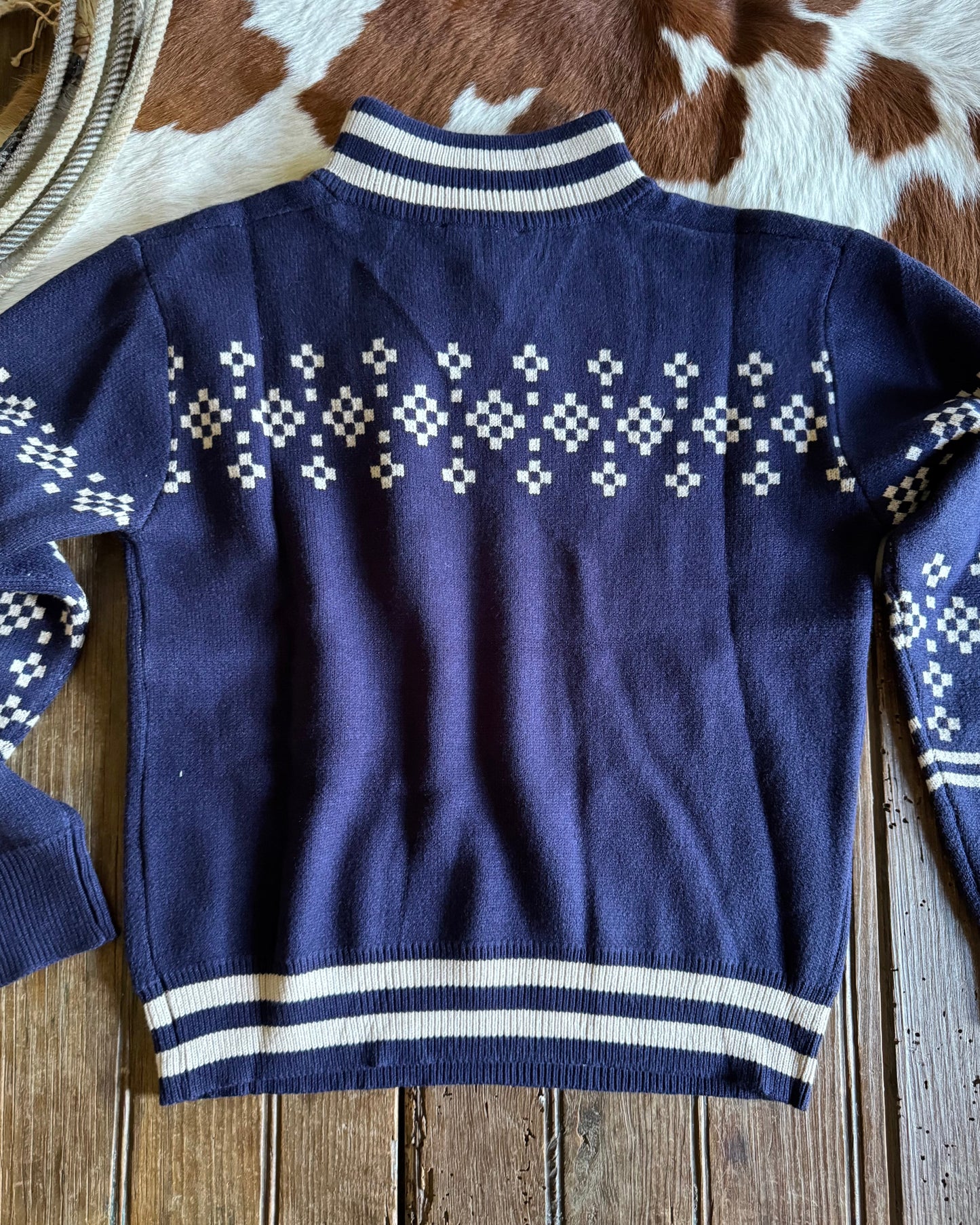 Navy blue sweater with white pattern on a wooden surface