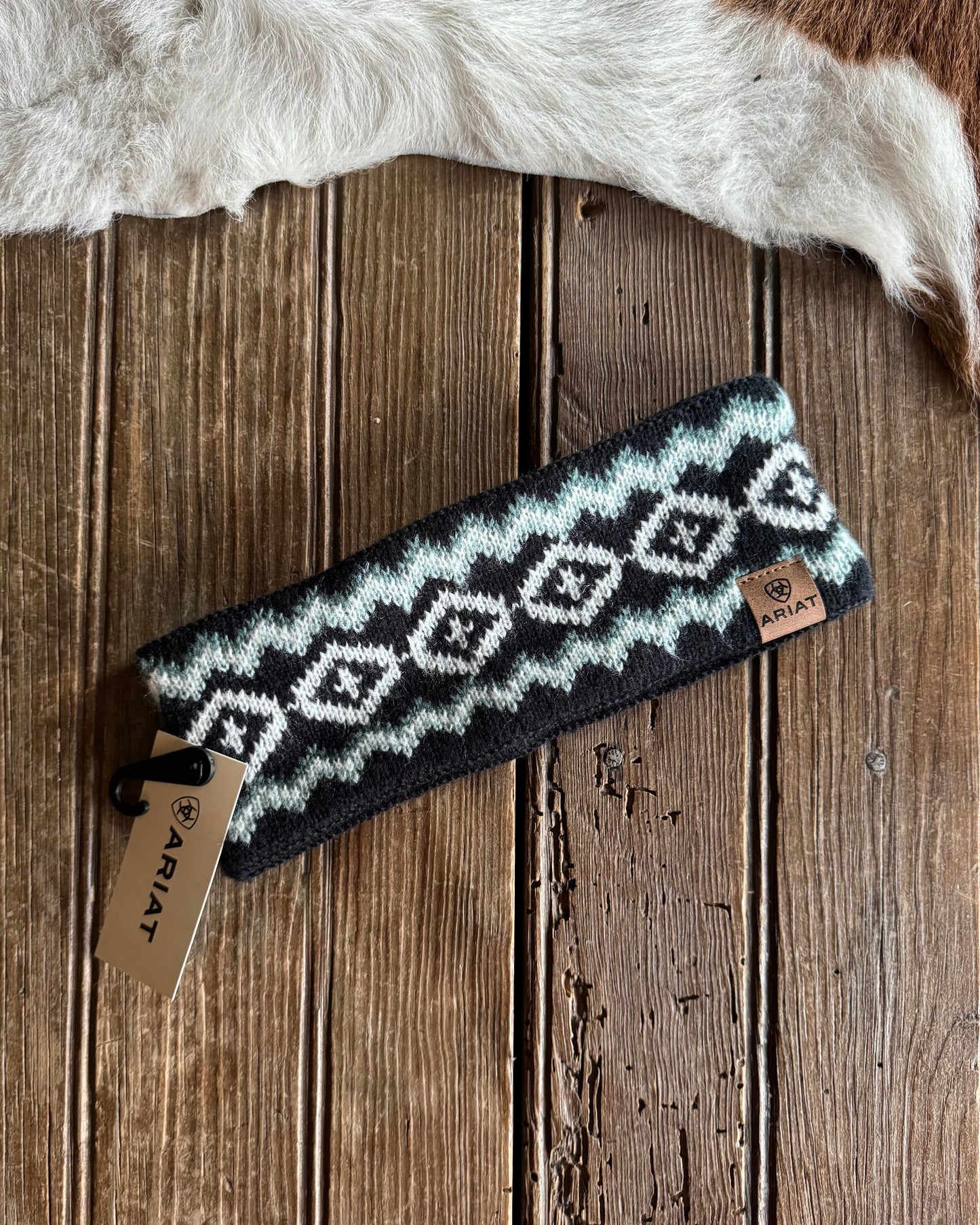 Knitted headband with a geometric pattern on a wooden surface with fur in the background