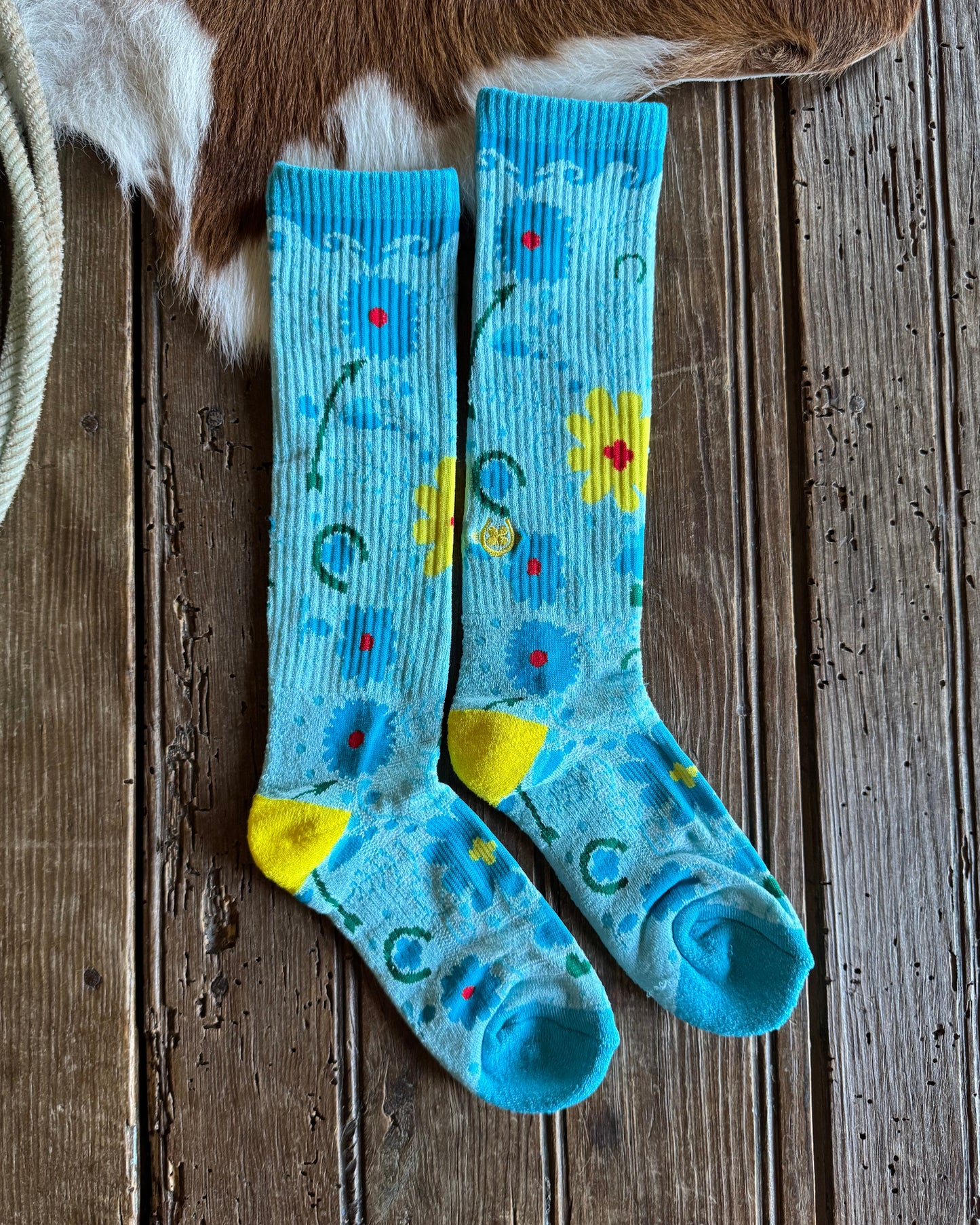 Pair of blue socks with floral patterns on a wooden surface