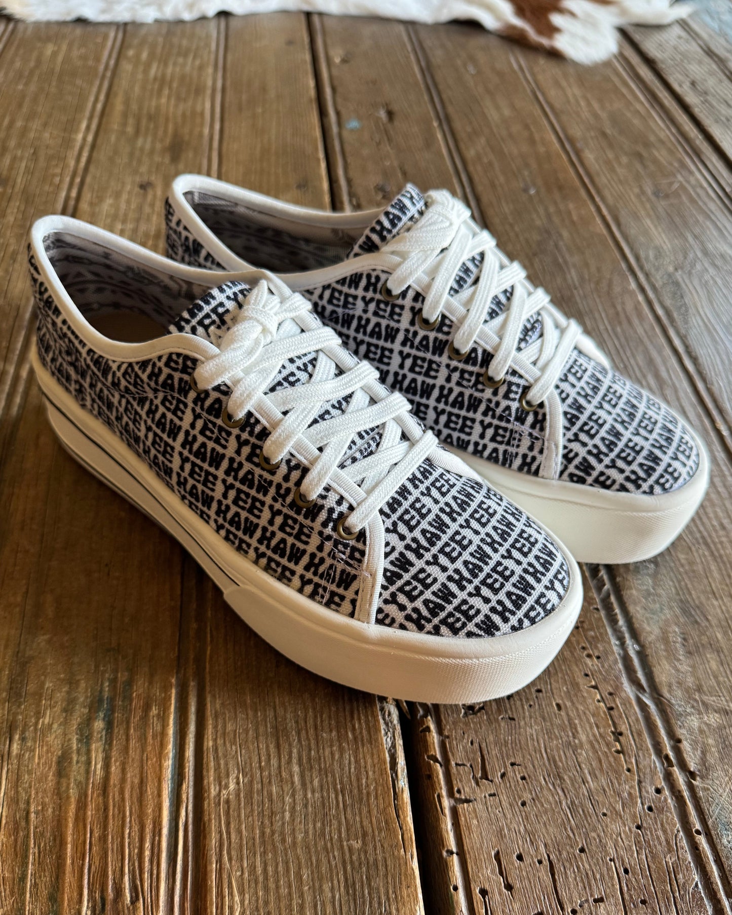 side view of yeehaw printed sneakers with rustic wood background