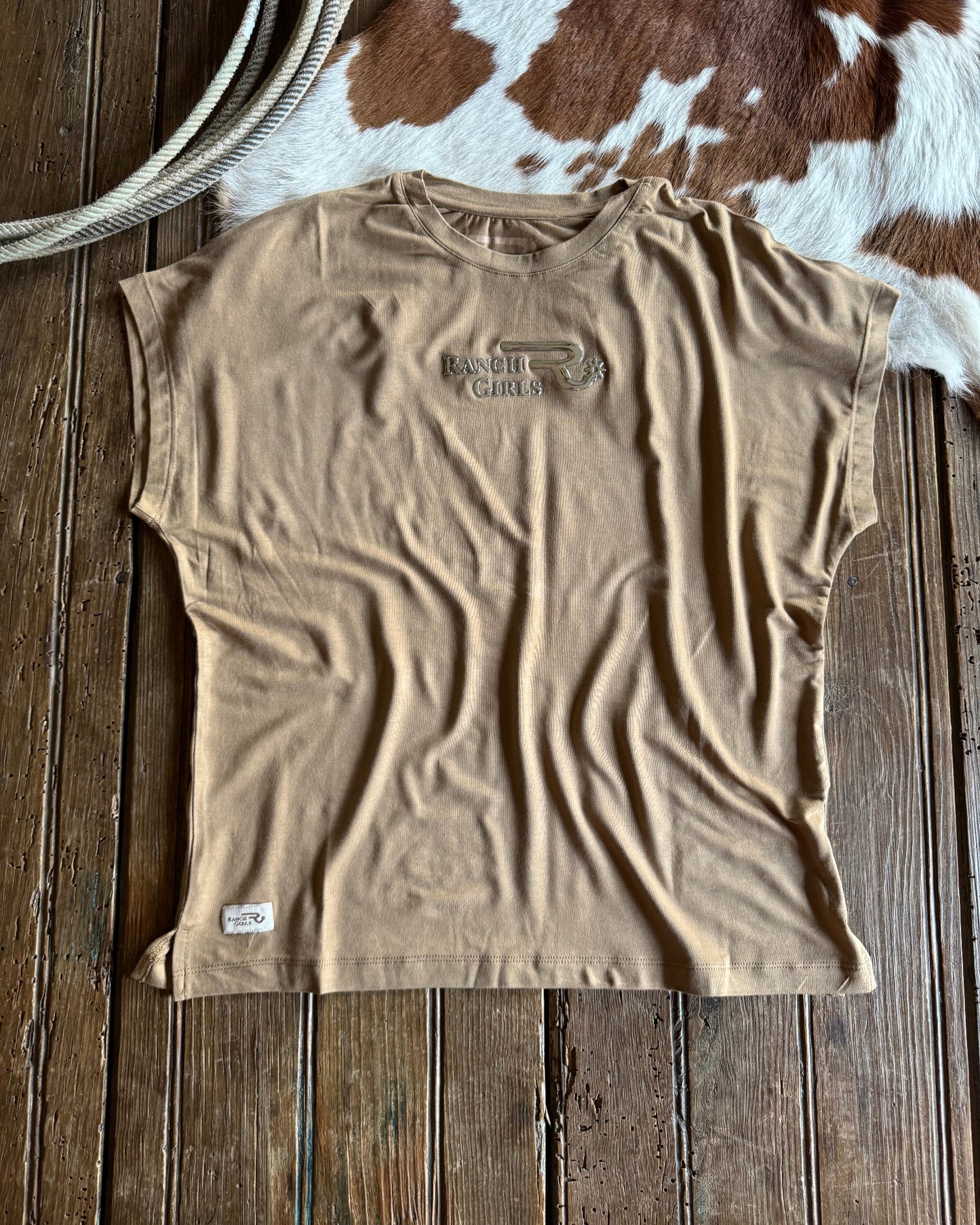 Beige tank top with branding on a wooden surface