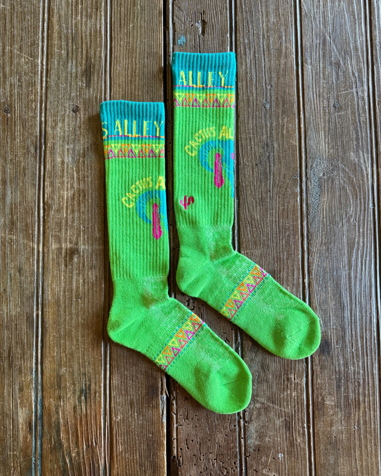 Cactus Alley Southwest Green Performance Socks on rustic wood background