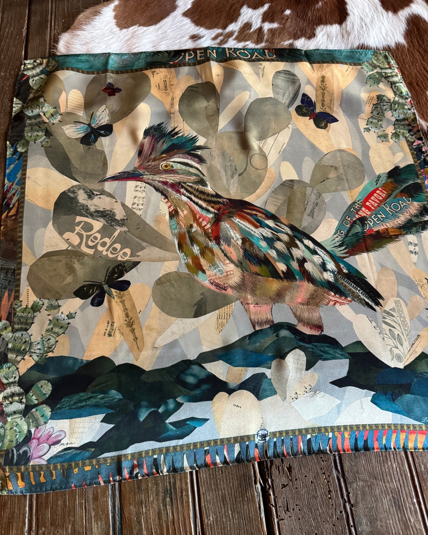 Collage scarf with feathers and nature-themed elements on a wooden surface