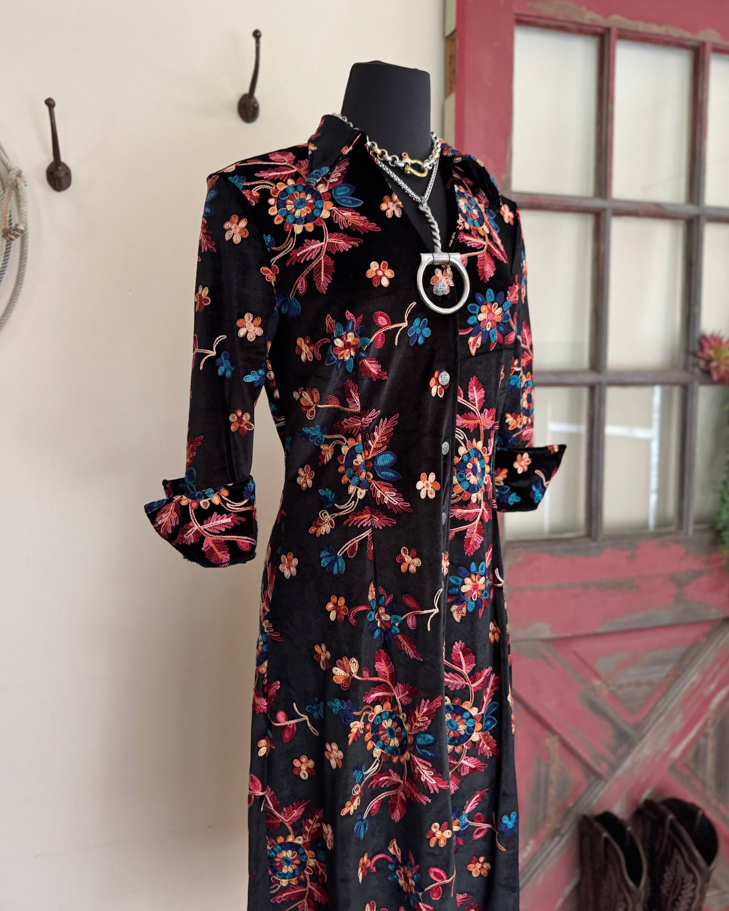Floral dress on a mannequin against a neutral wall with a window in the background.