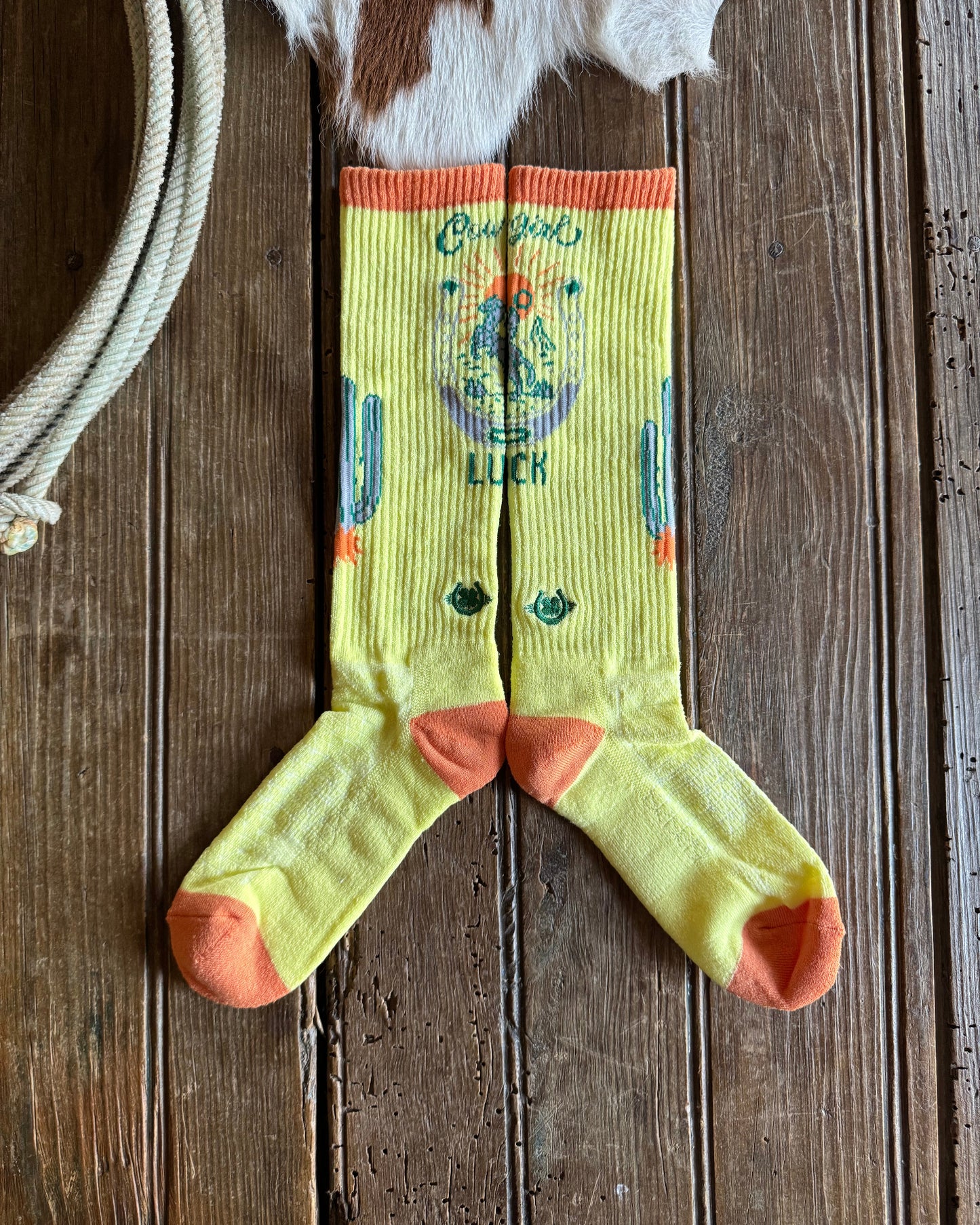 Pair of yellow socks with orange accents on a wooden surface
