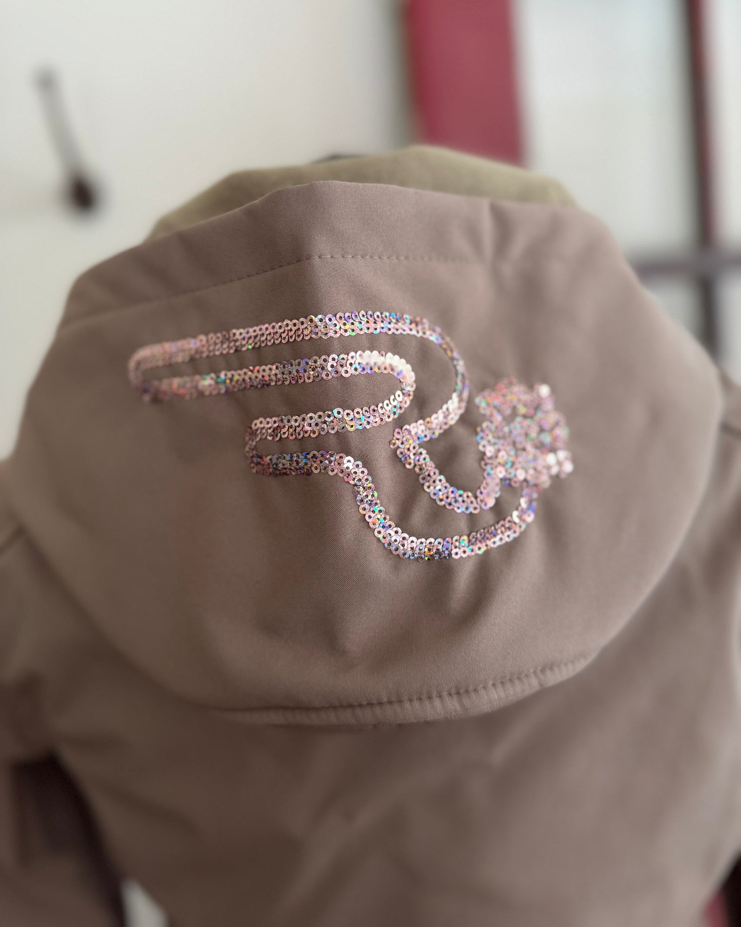 Brown jacket with decorative lettering on the back against a neutral background