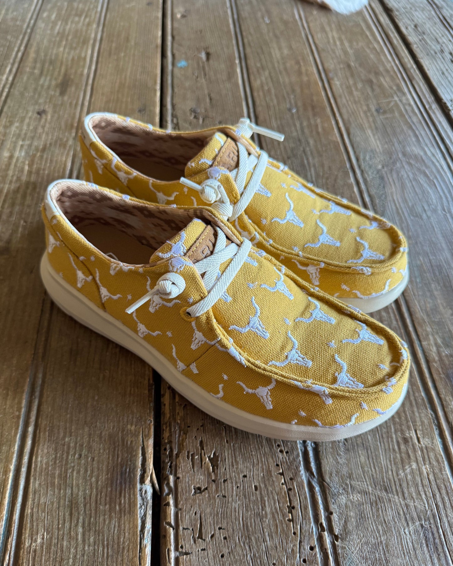 embroidered steer head sneakers on rustic wood background