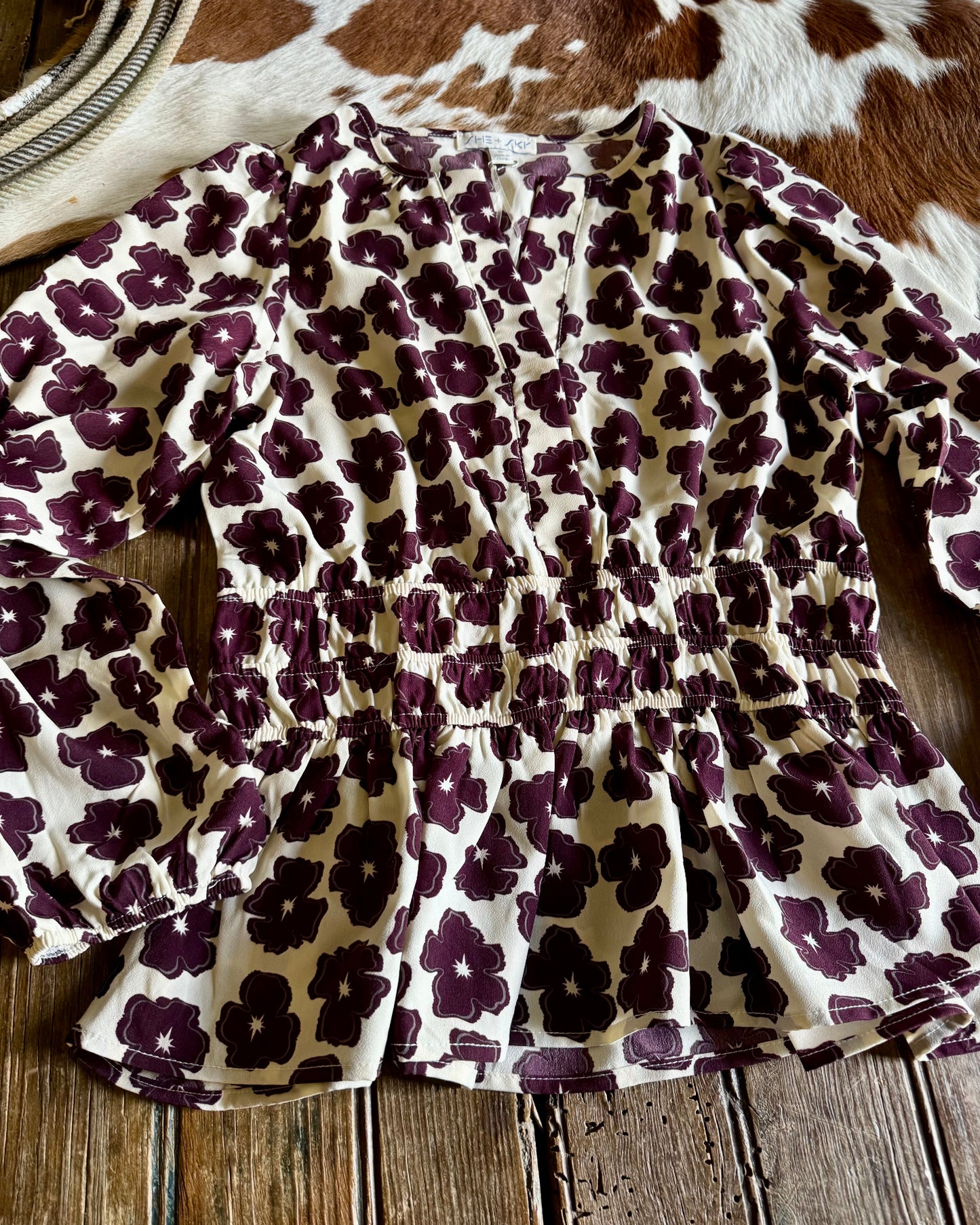 Floral print top on a wooden surface with a cowhide rug in the background