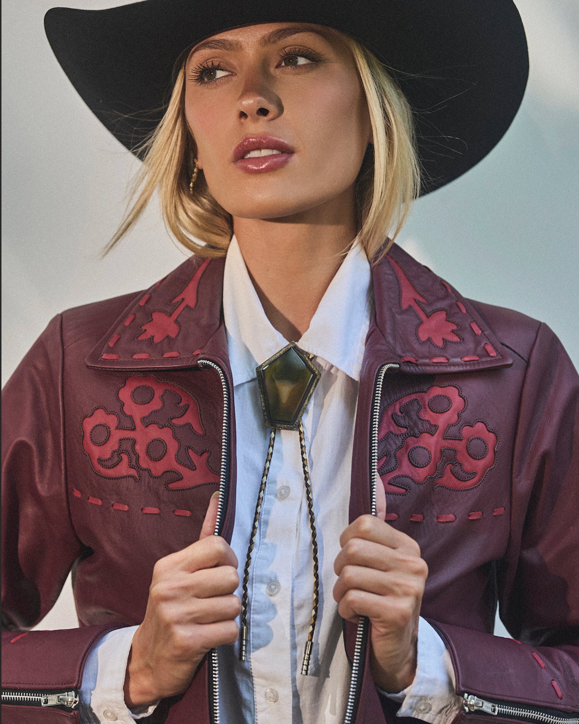 Woman wearing a stylish cowboy hat and leather jacket.
