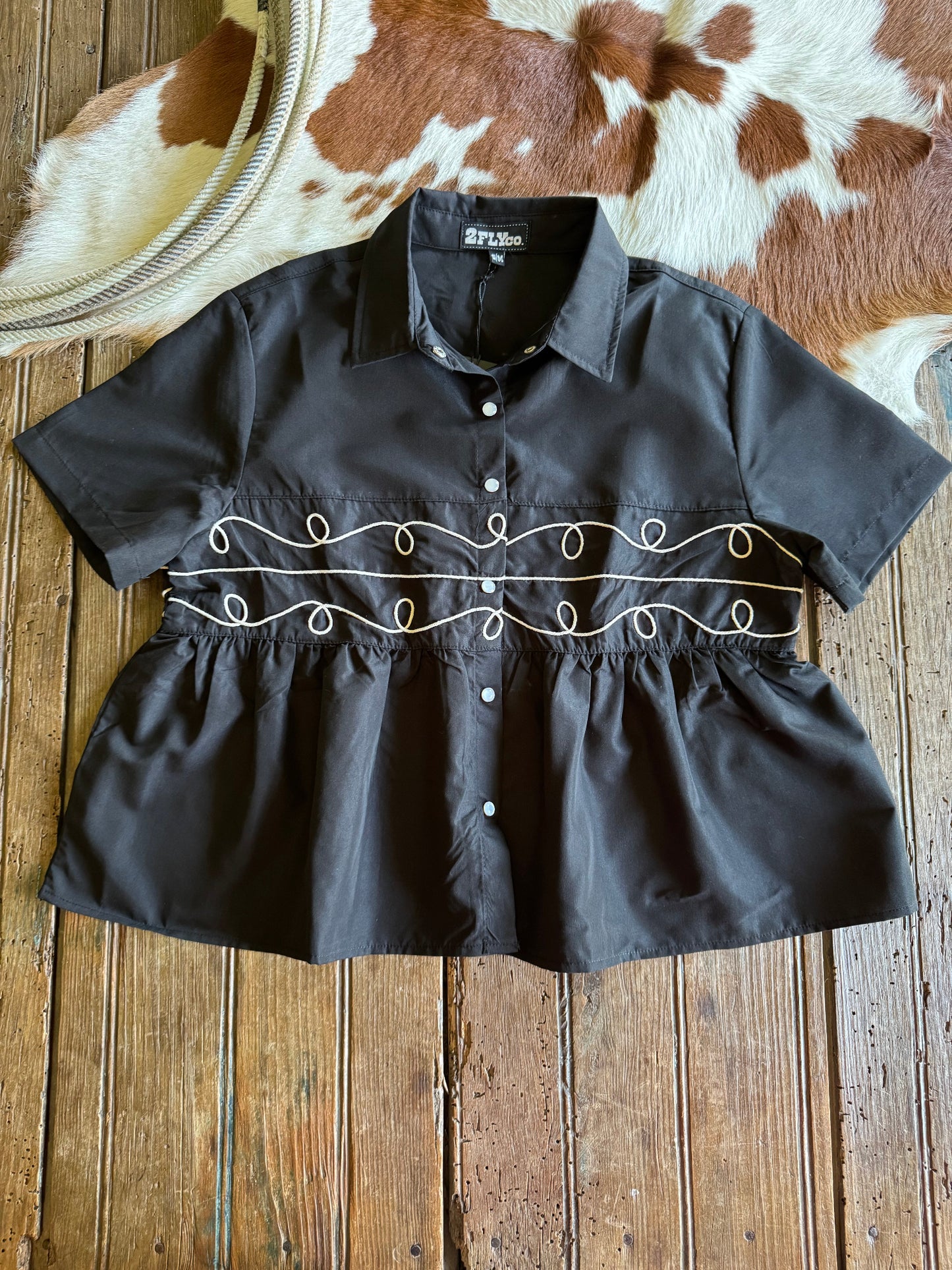 Black blouse with decorative embroidery on a wooden surface