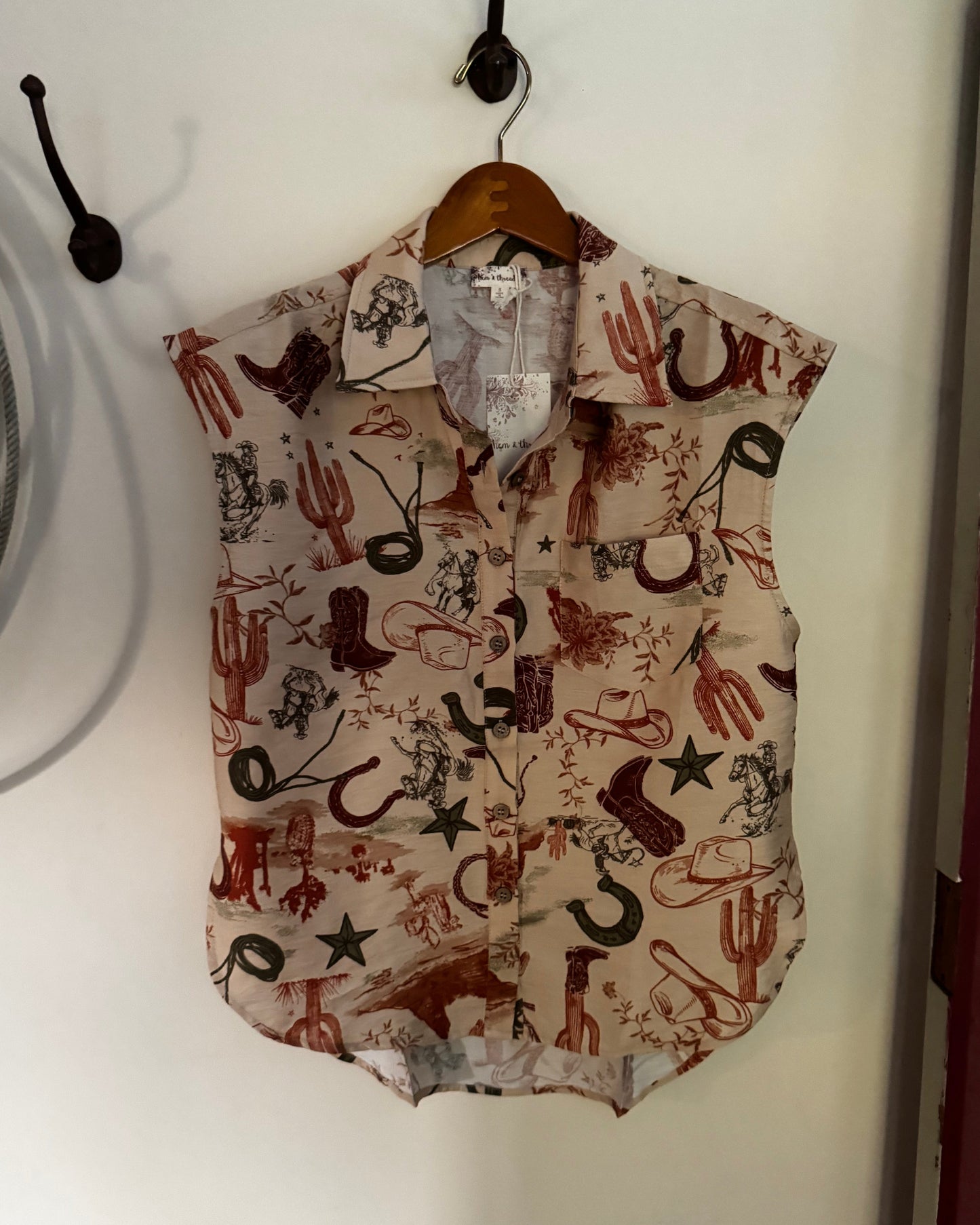Sleeveless blouse with western print hanging on a white wall