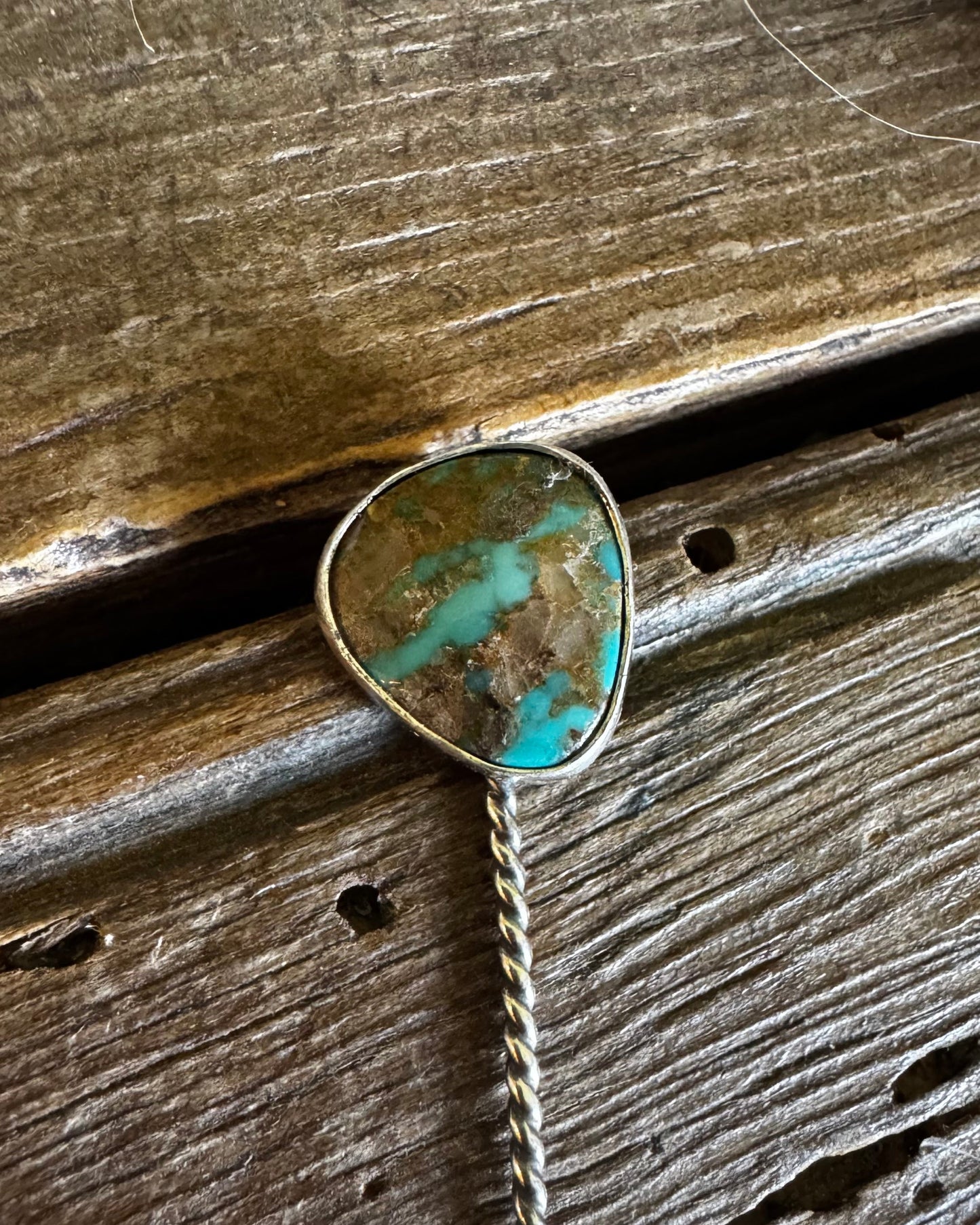 Turquoise stone brooch on a wooden surface