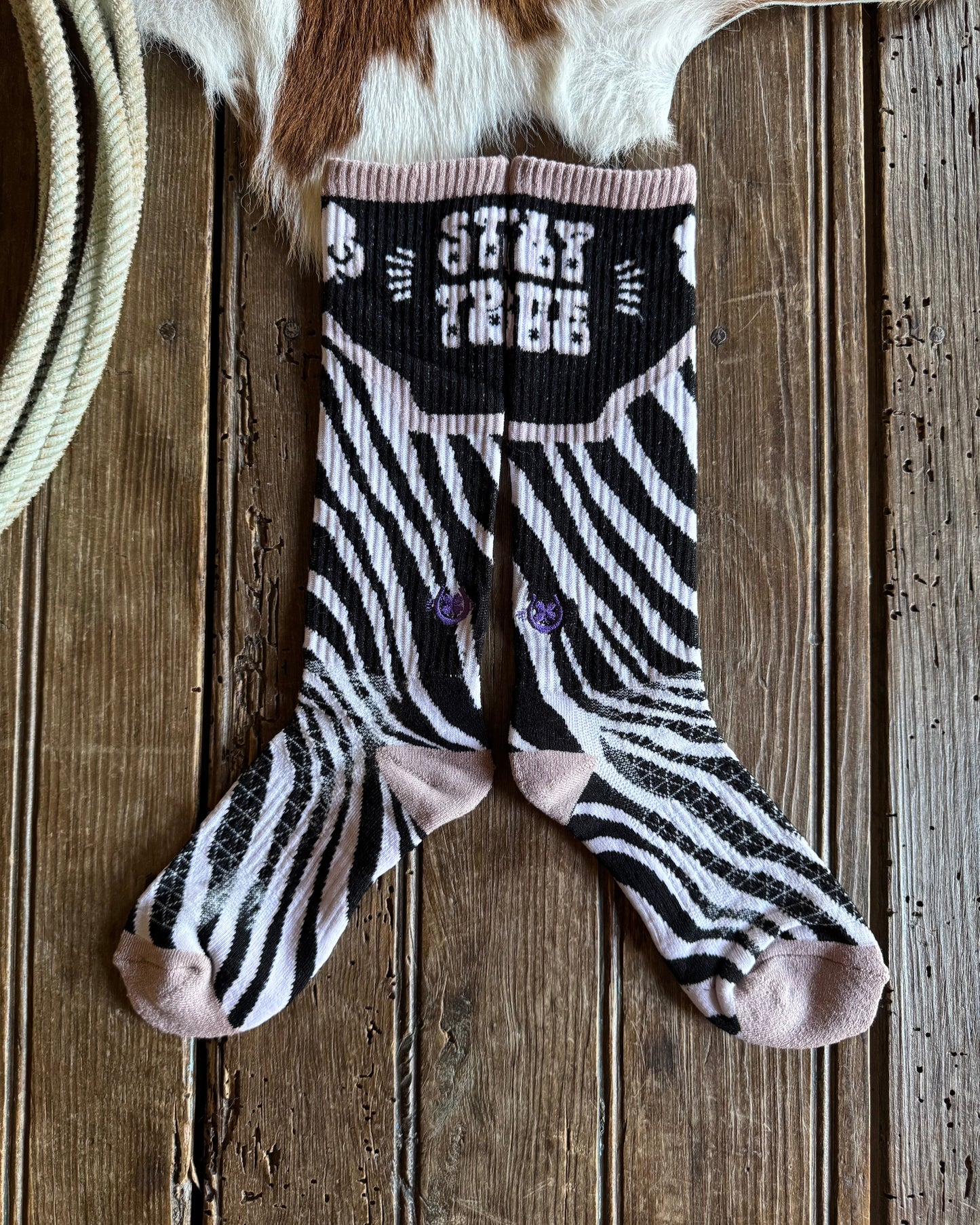 Zebra-patterned sock on a wooden surface with cowhide rug in the background