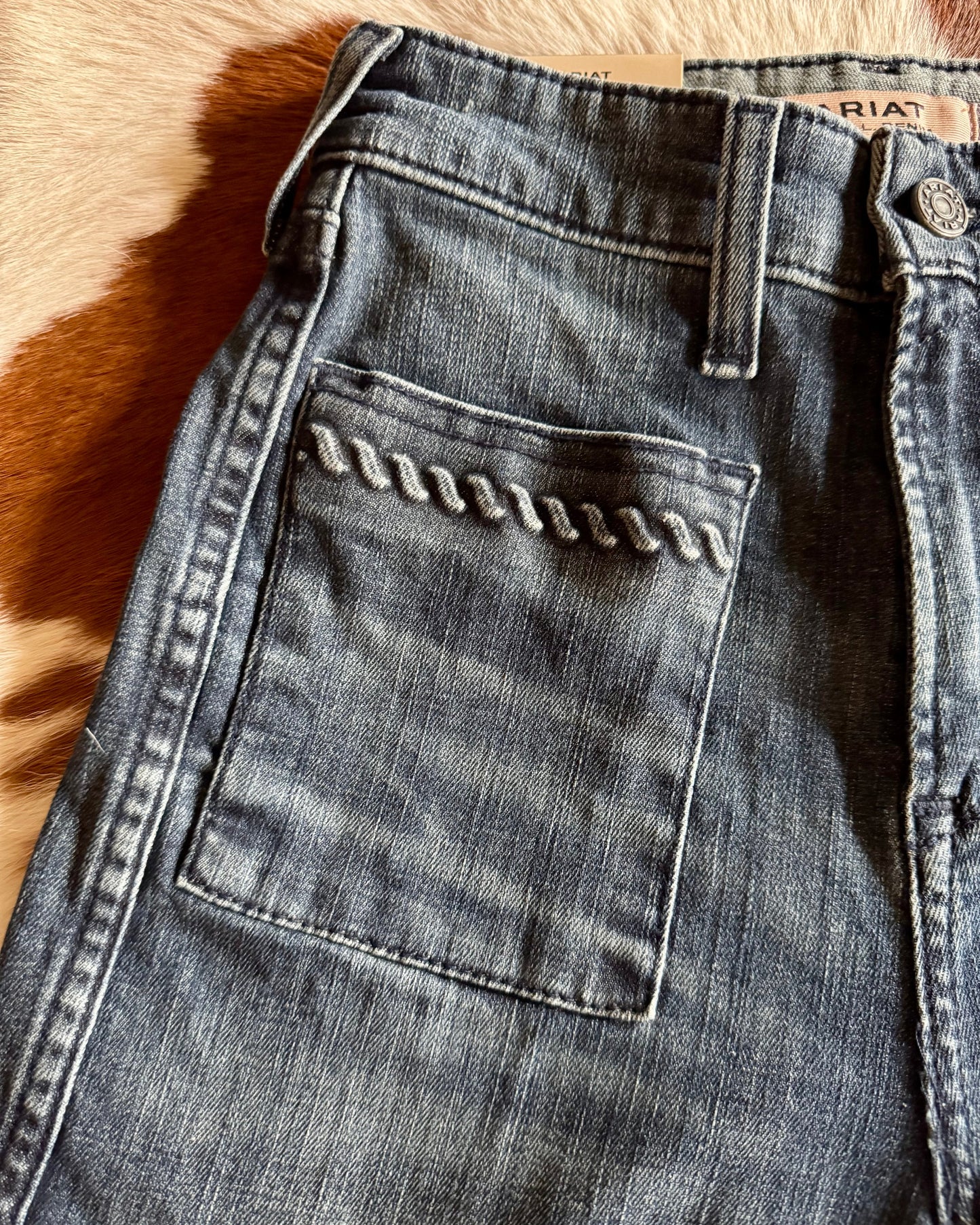Close-up of a pair of blue jeans with a visible brand label on a textured surface.