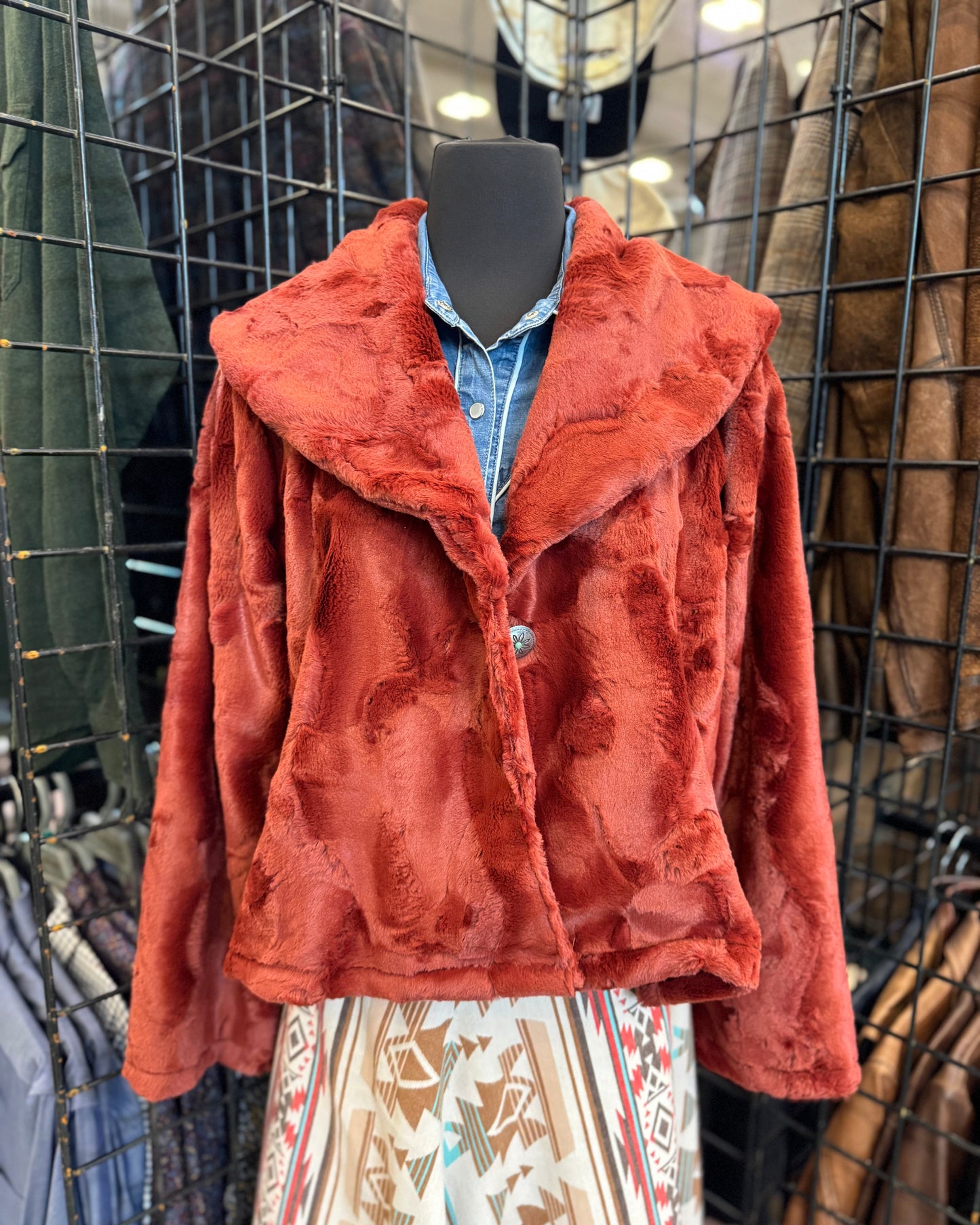 Red jacket on a mannequin with a patterned skirt in a store setting