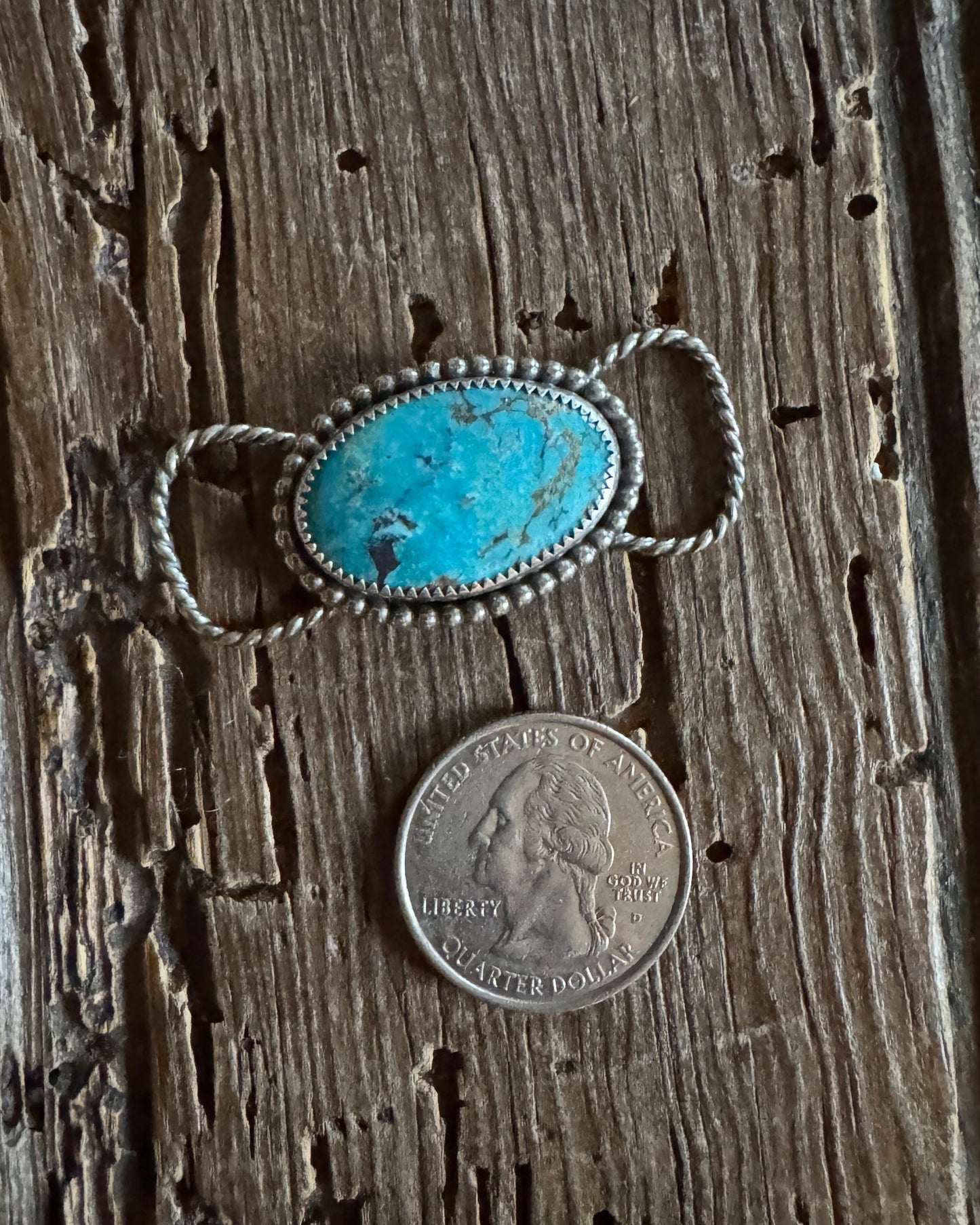 Turquoise stone twilly slide next to a quarter on wooden surface