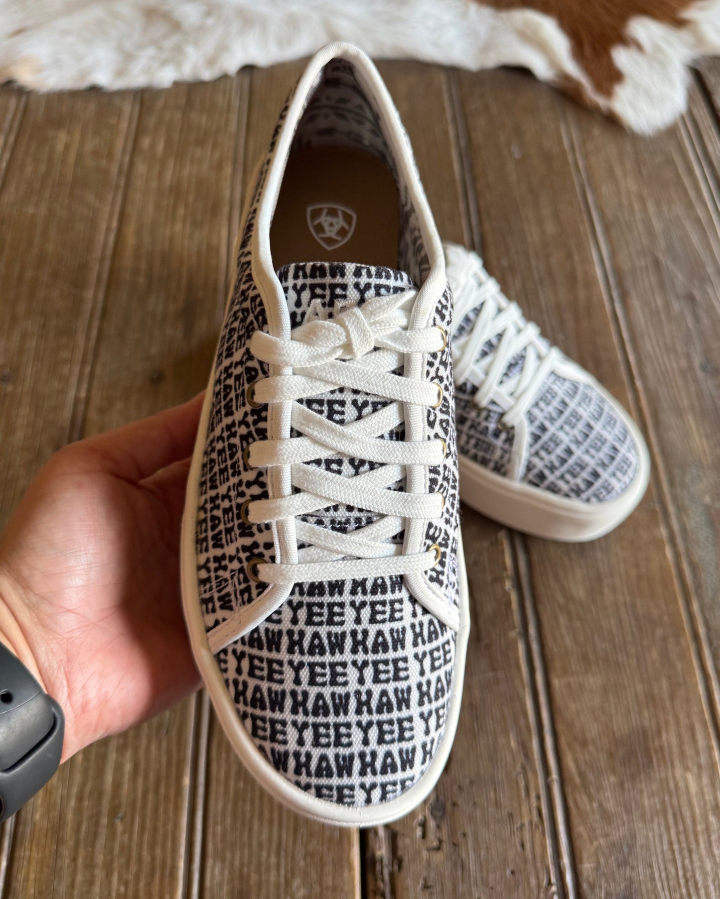 Top closeup of yeehaw printed sneakers with rustic wood background