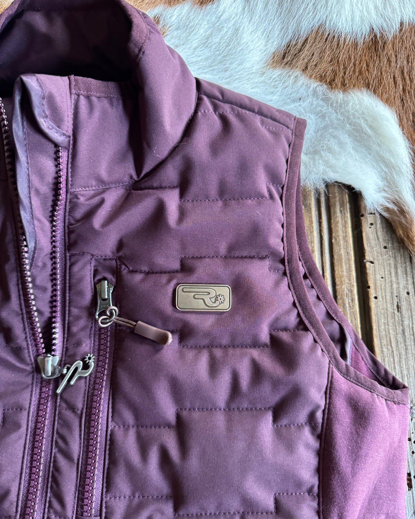 Purple quilted jacket with a brand logo on a textured surface