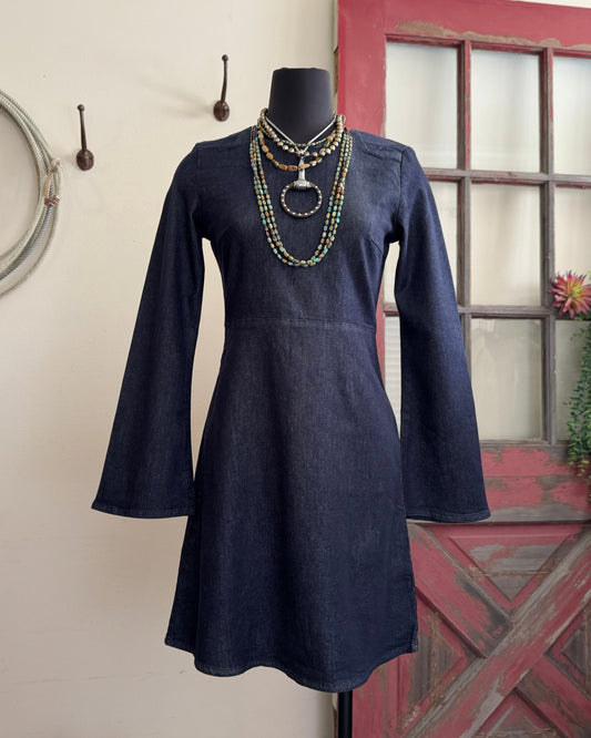 Navy blue dress on a mannequin with necklaces against a neutral wall.