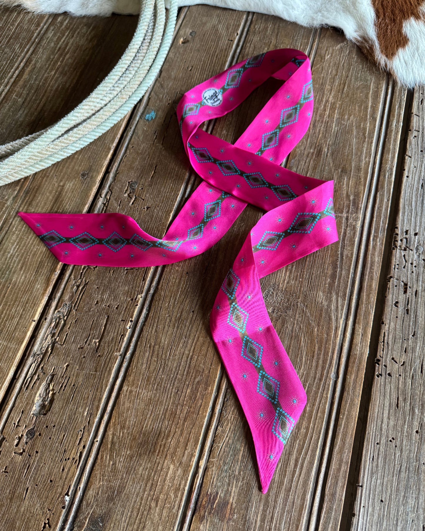 Pink ribbon scarf with geometric patterns on a wooden surface