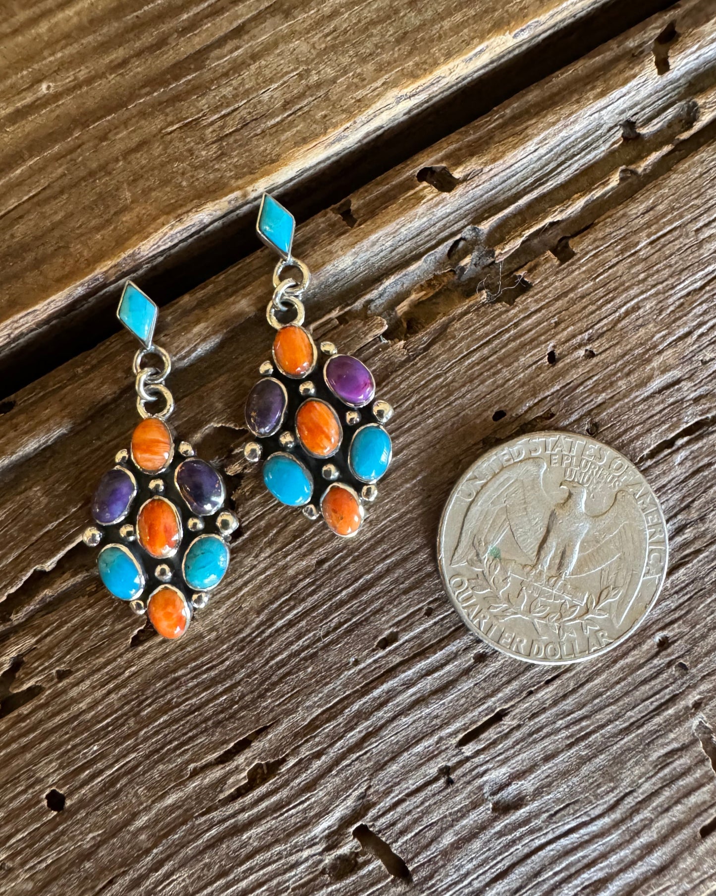 Sterling silver cluster earrings with turquoise, orange and purple spiny next to quarter on rustic wood background