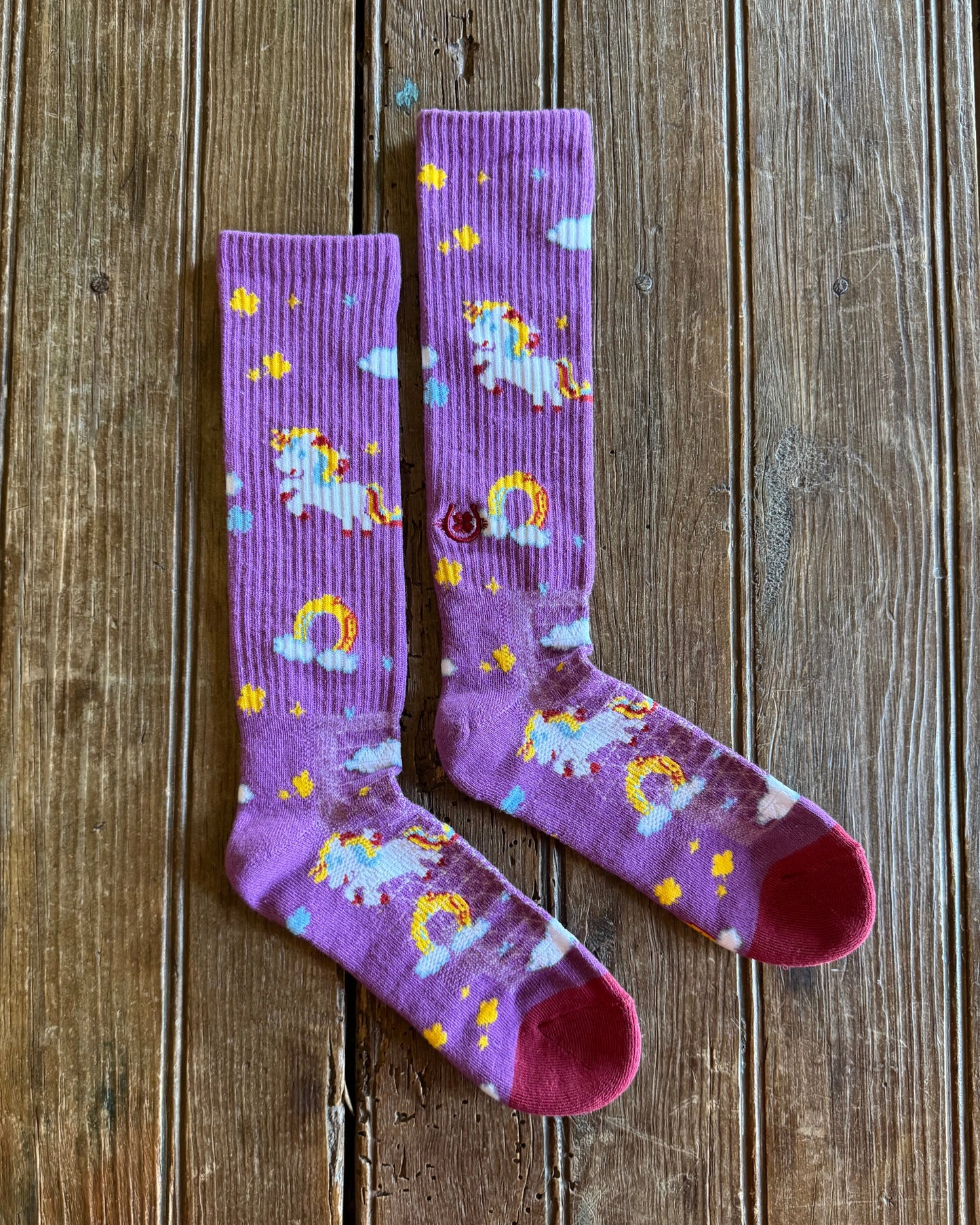 Lucky Unicorns Performance Socks in purple on rustic wood background