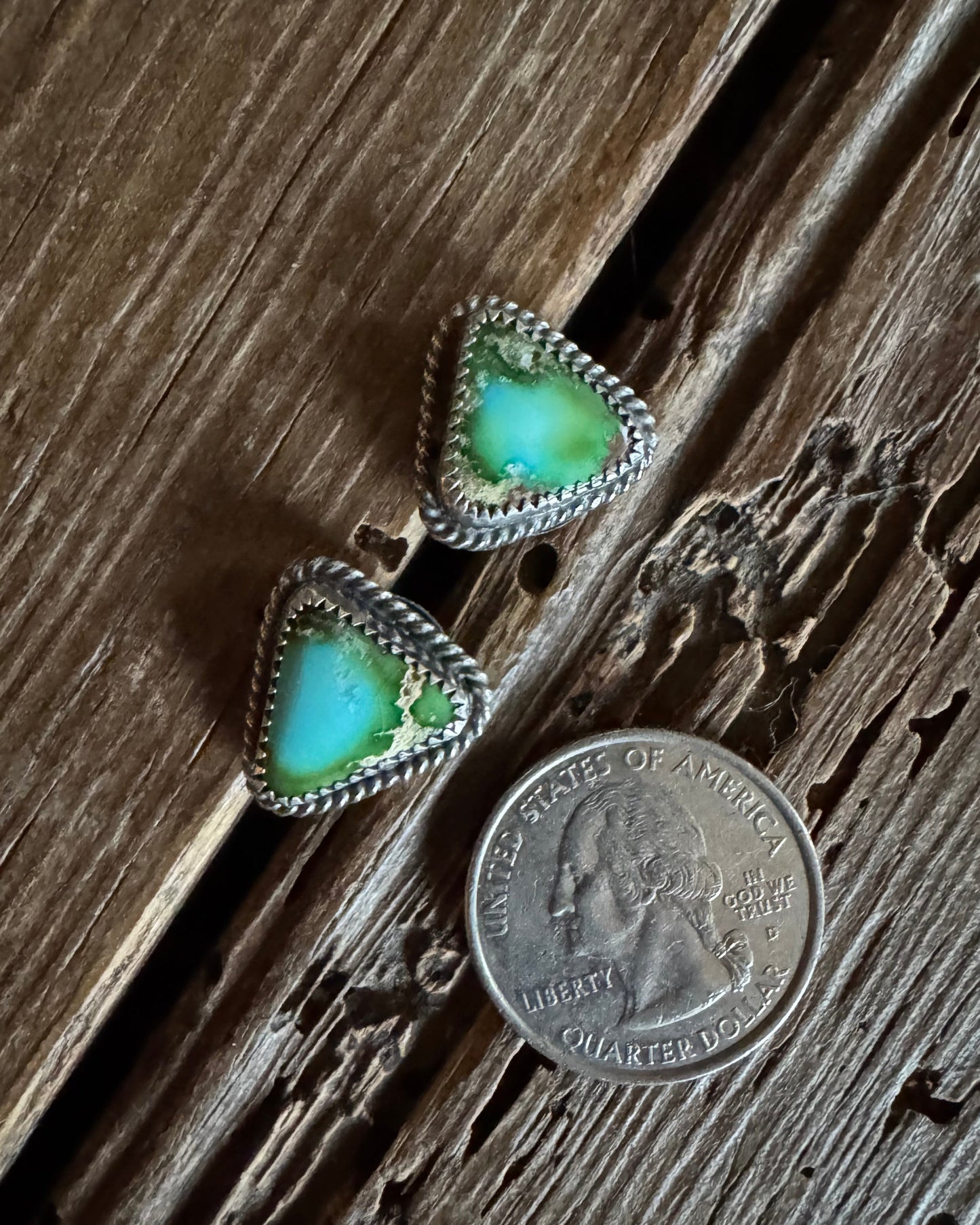 Turquoise triangle earrings with silver accents on a wooden surface next to a quarter for scale.