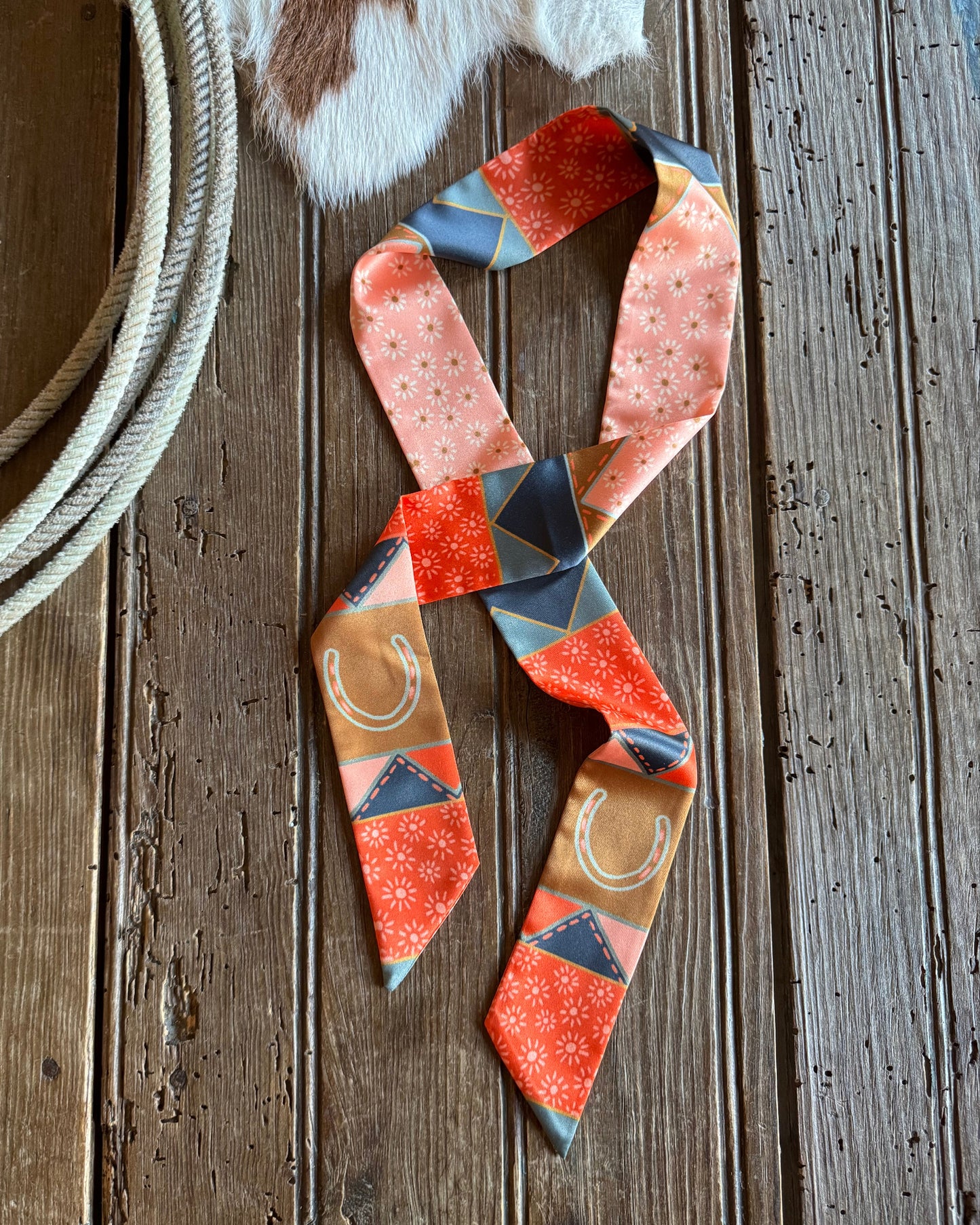 Patchwork ribbon scarf on a rustic wooden background with a rope