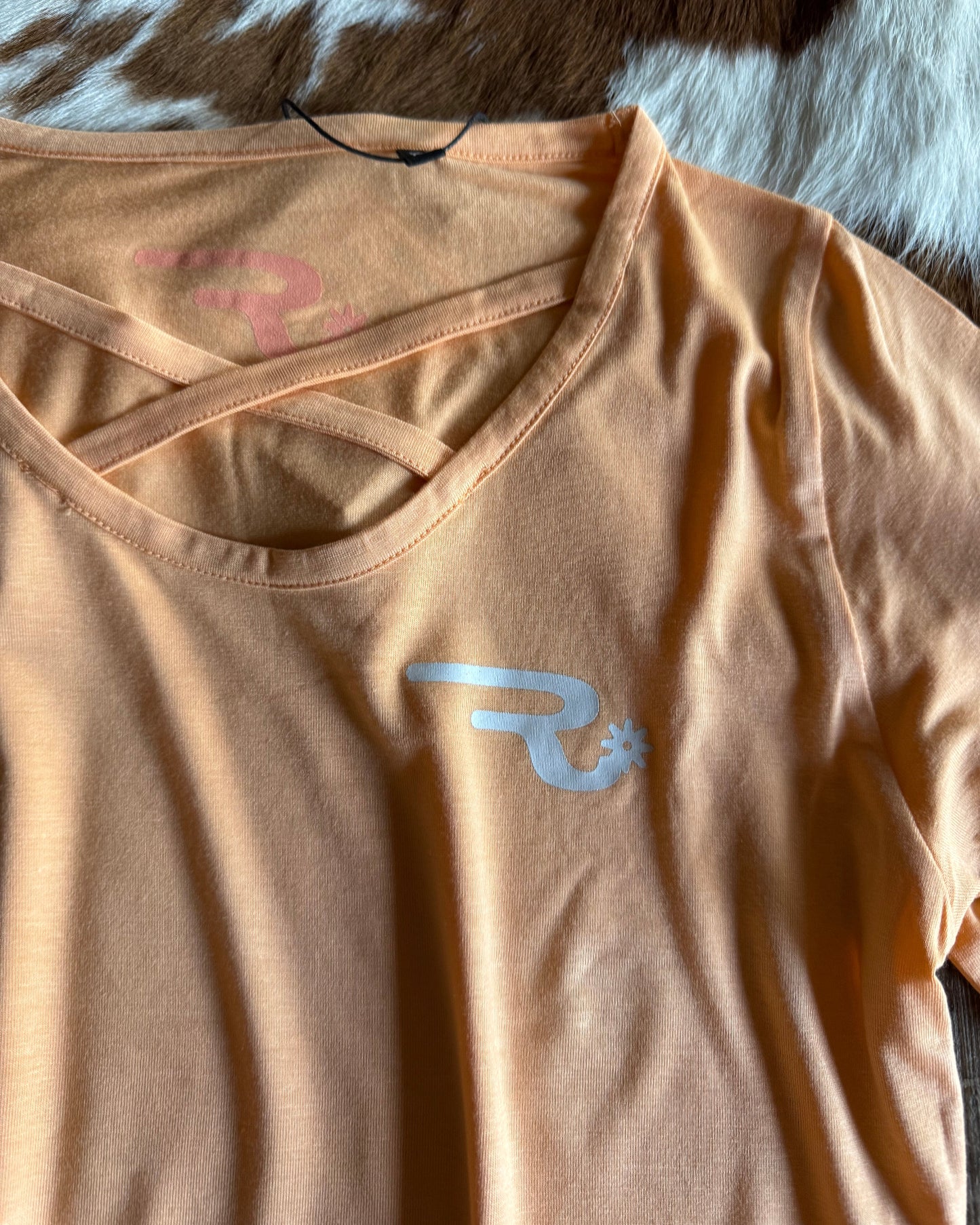 Beige athletic shirt with a logo on a patterned surface