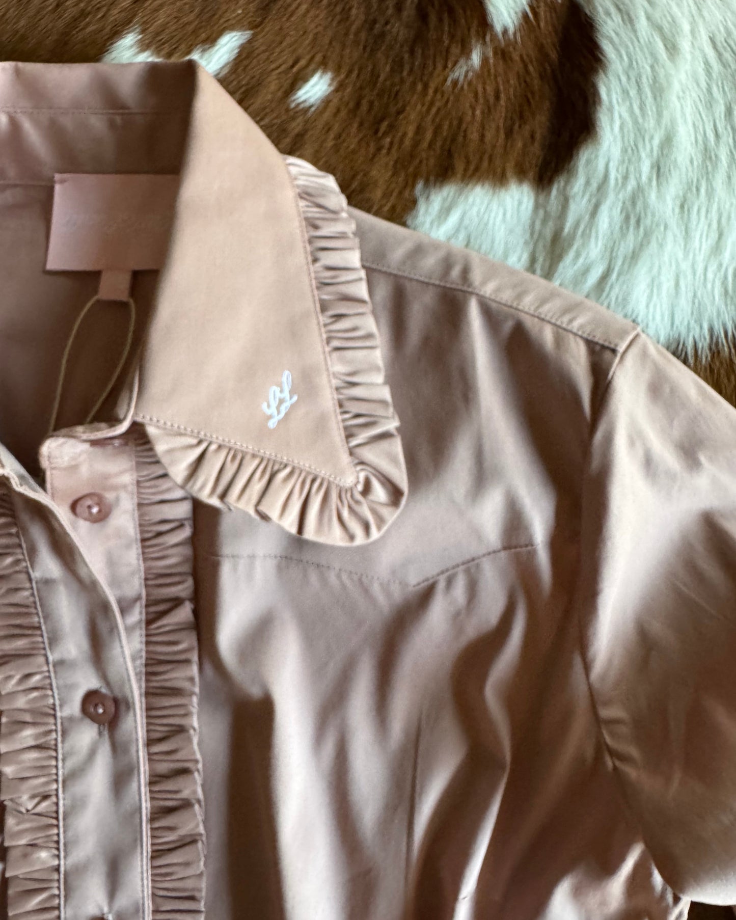 Close-up of a pink shirt with a brand logo on a textured surface