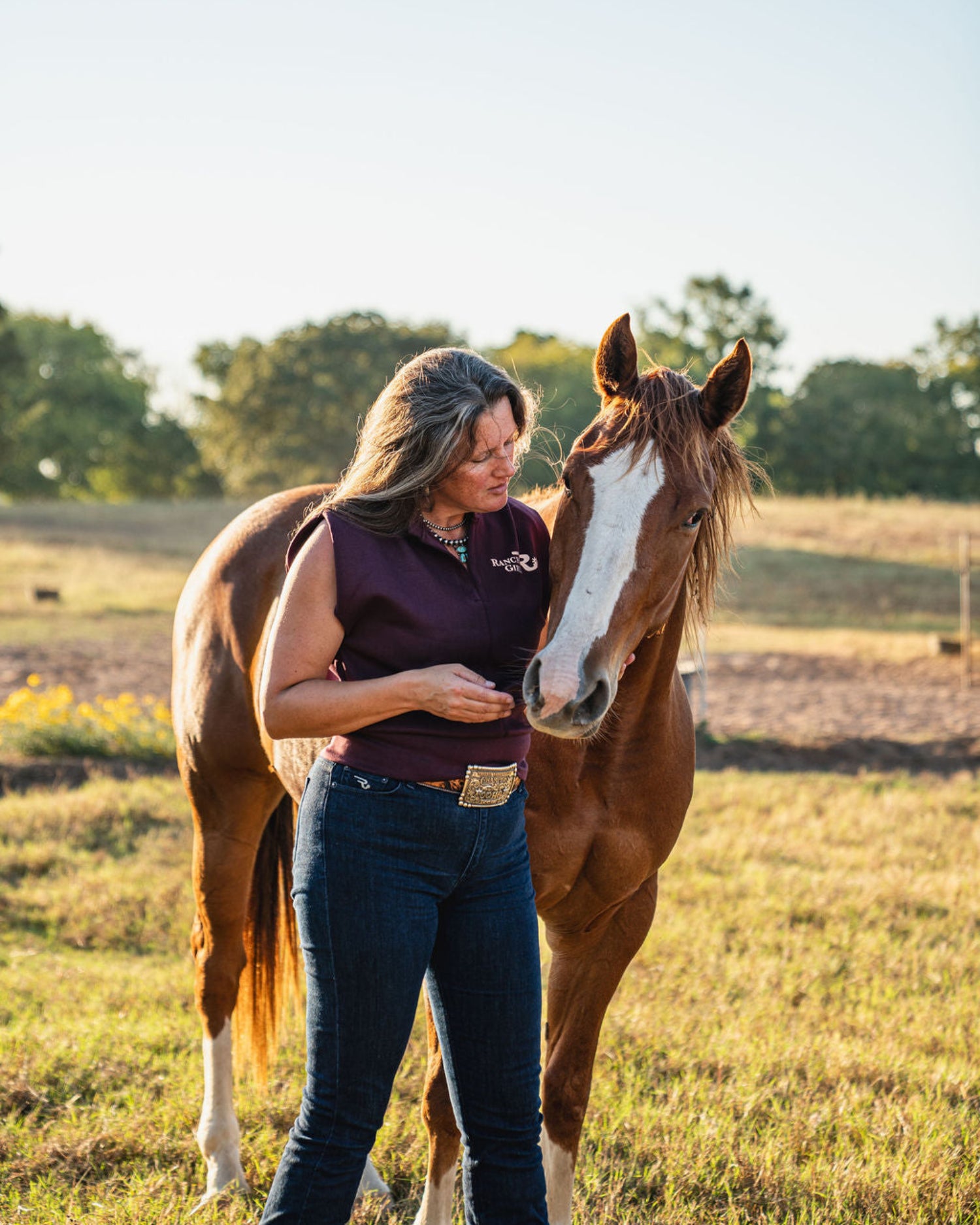 woman with horse standing in a pasture