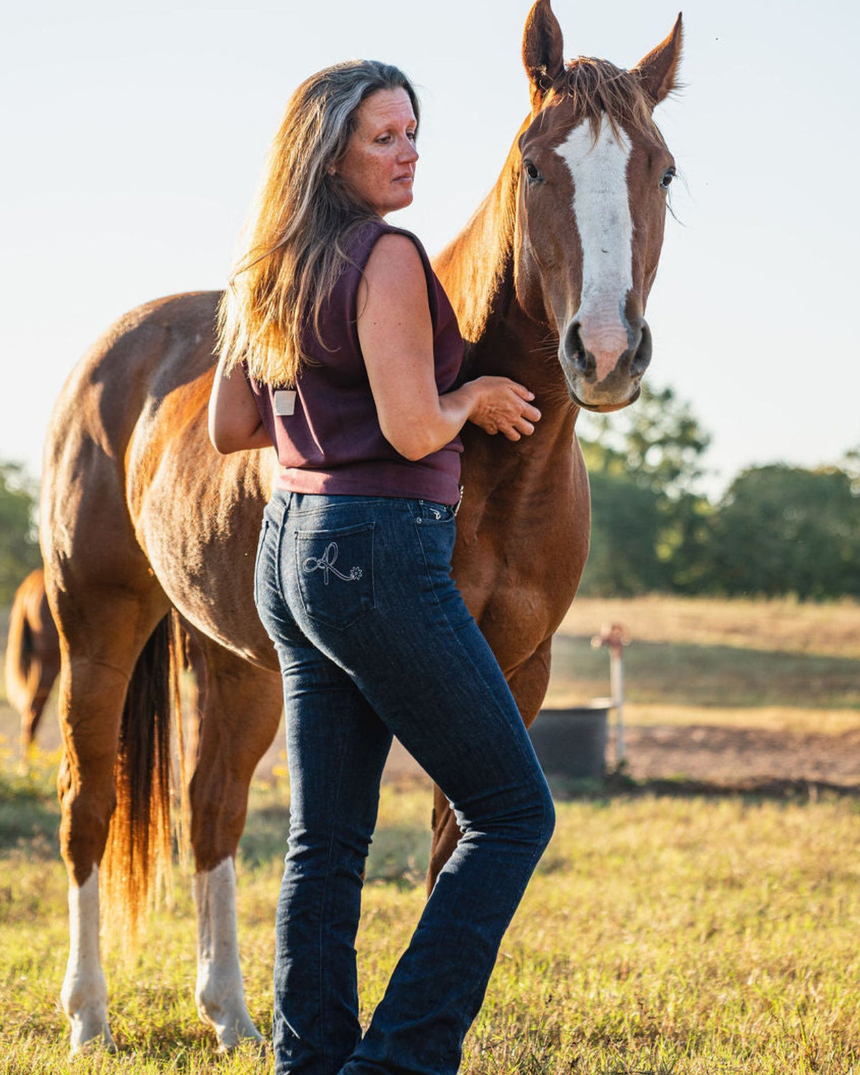 Woman standing next to a horse in an outdoor setting