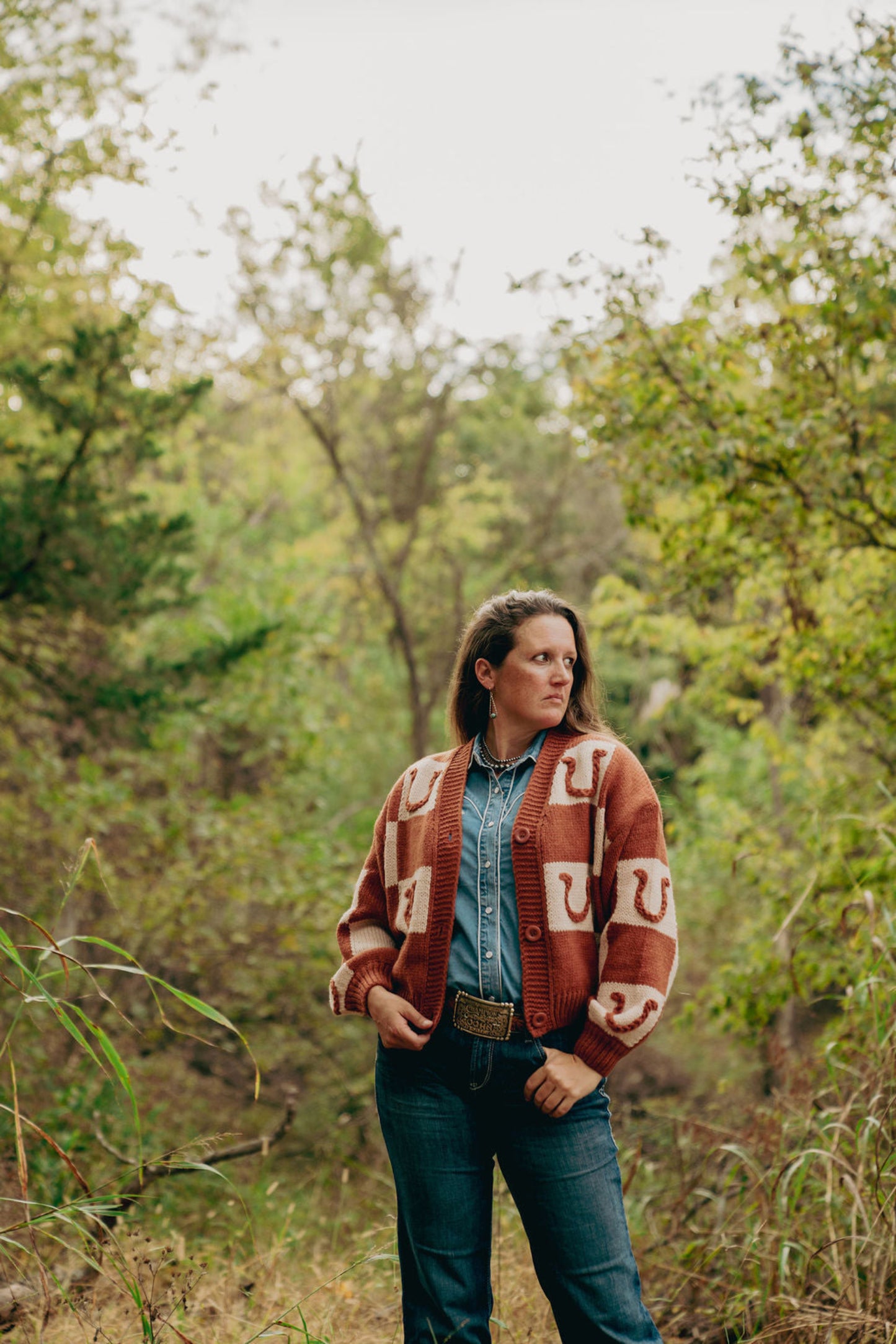 Person wearing a patterned sweater in a forest setting