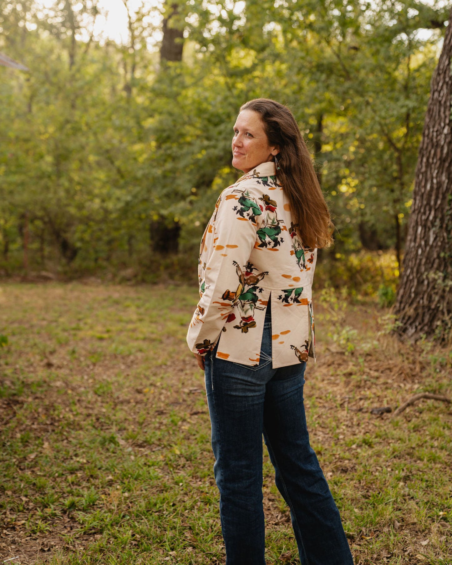 model wearing a coat and jeans standing in the woods