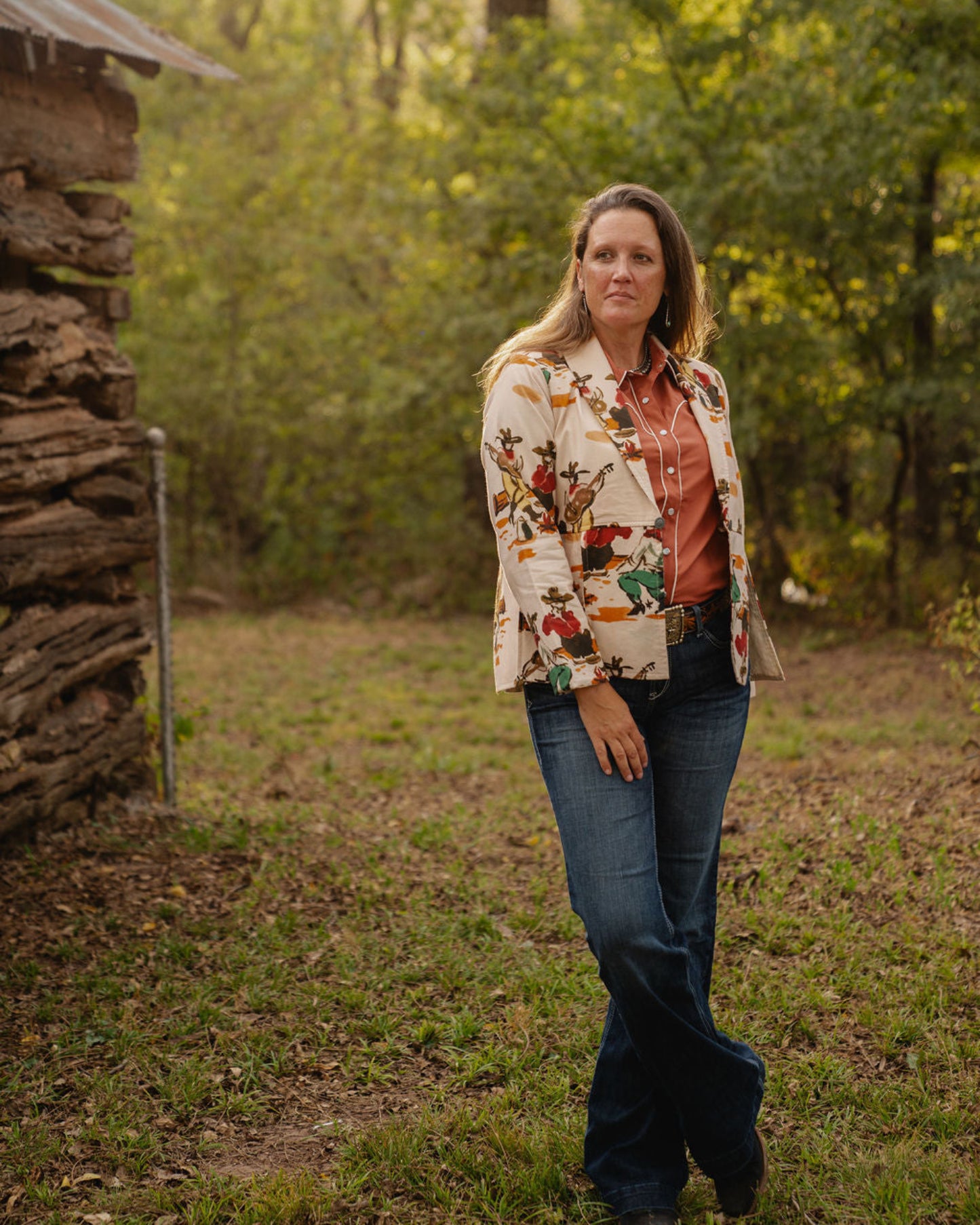 Woman standing outdoors in a natural setting wearing a floral jacket.