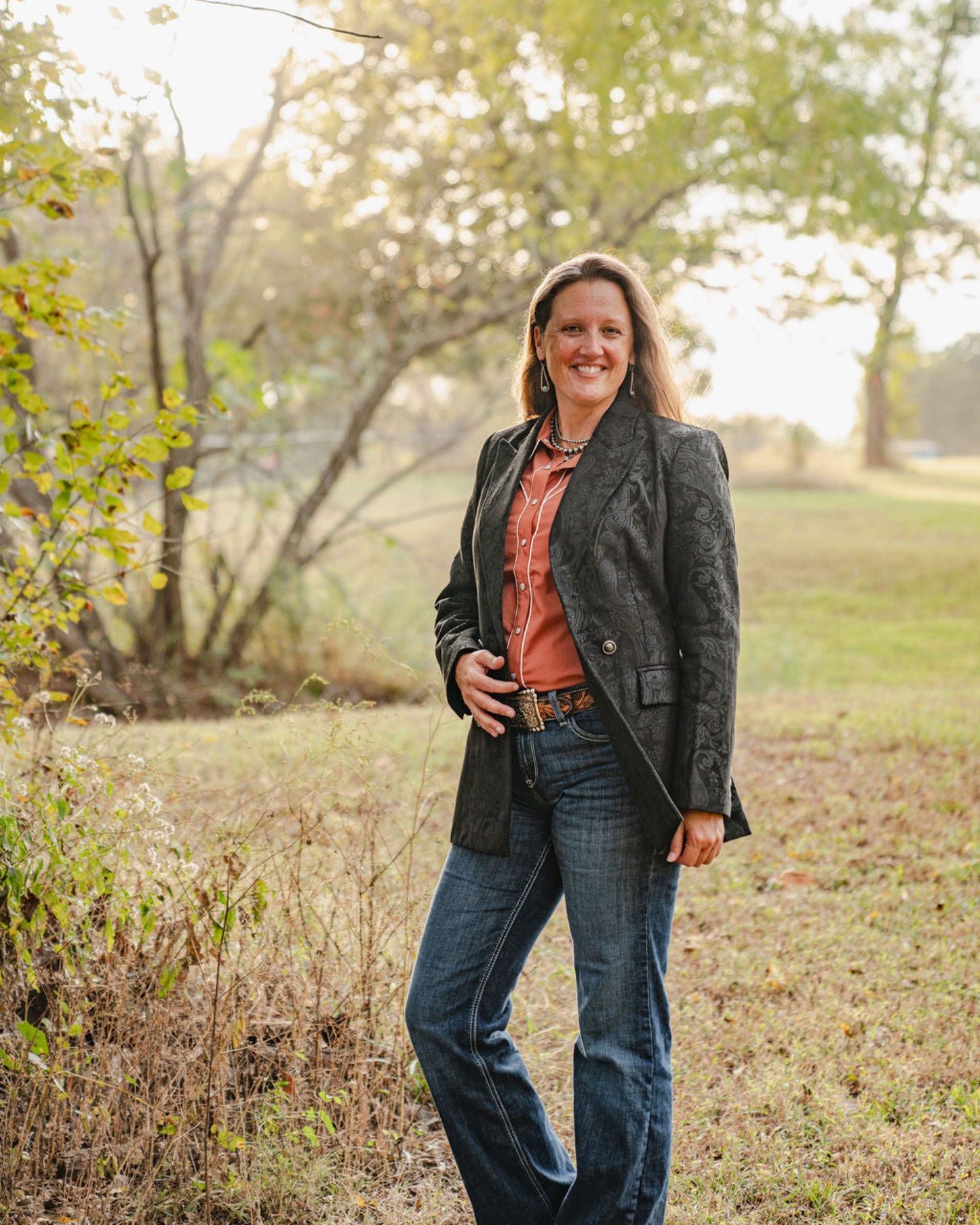 Woman standing in a field with trees in the background