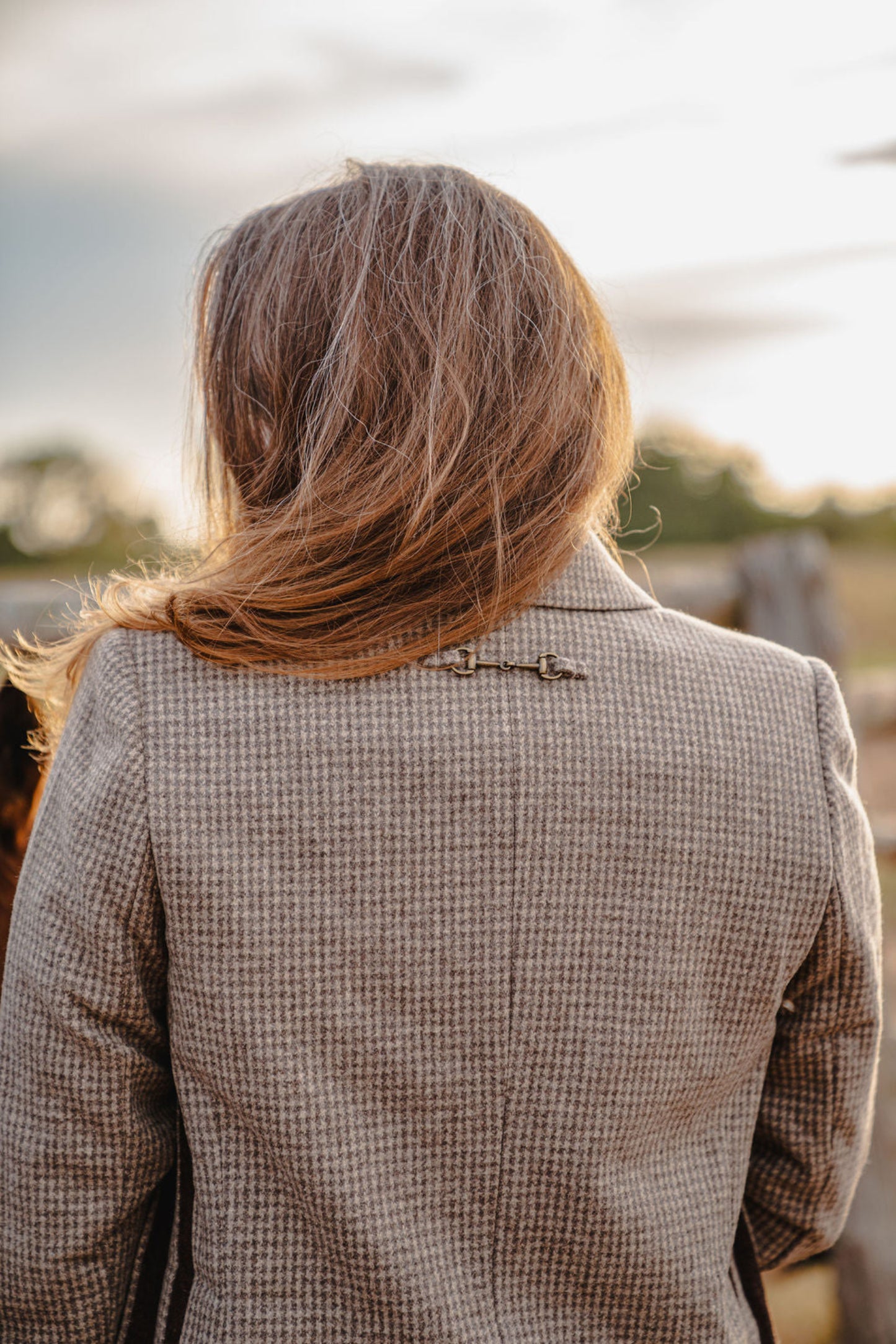 Person wearing a checkered blazer with a blurred natural background
