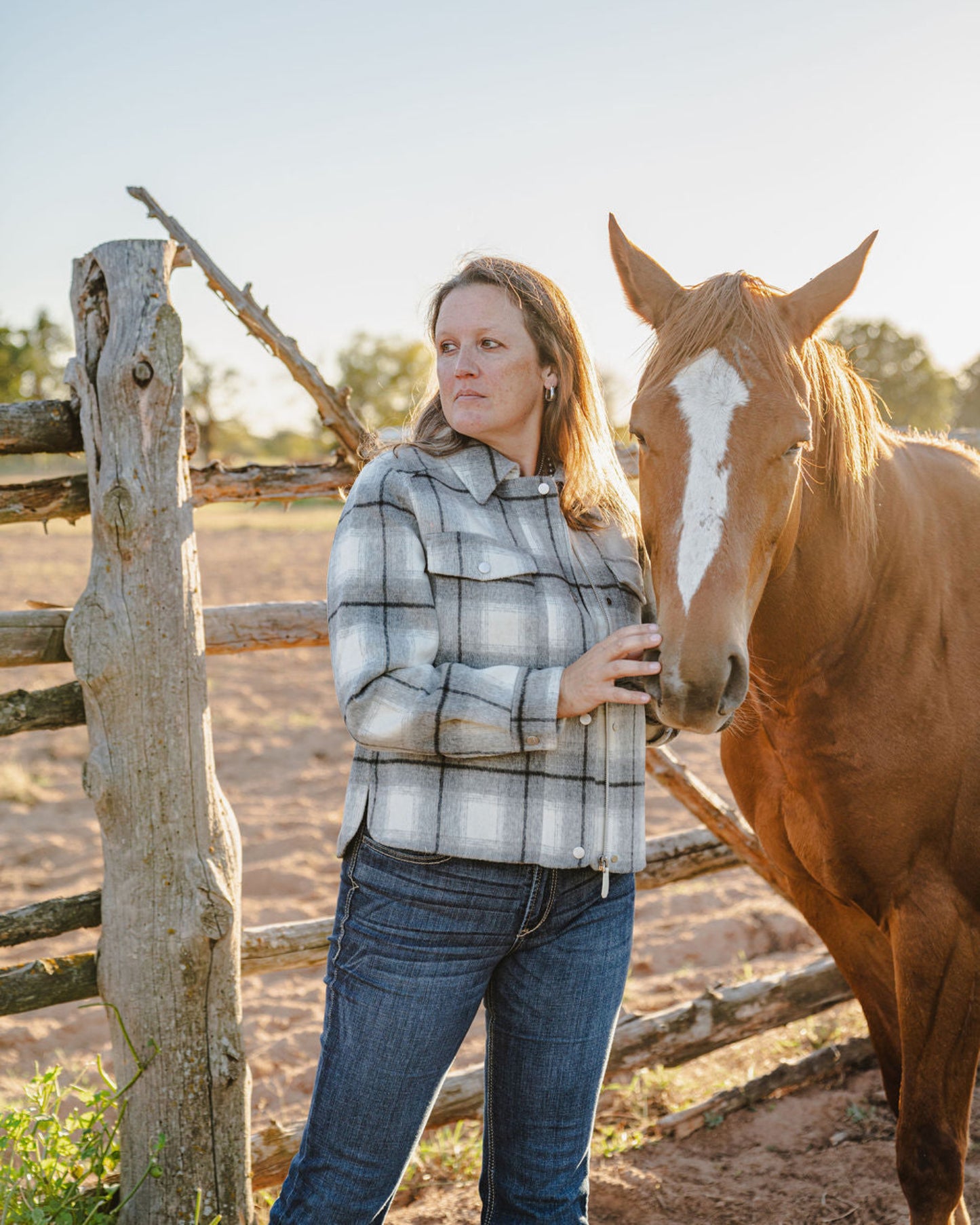 Woman standing next to a horse near a wooden fence