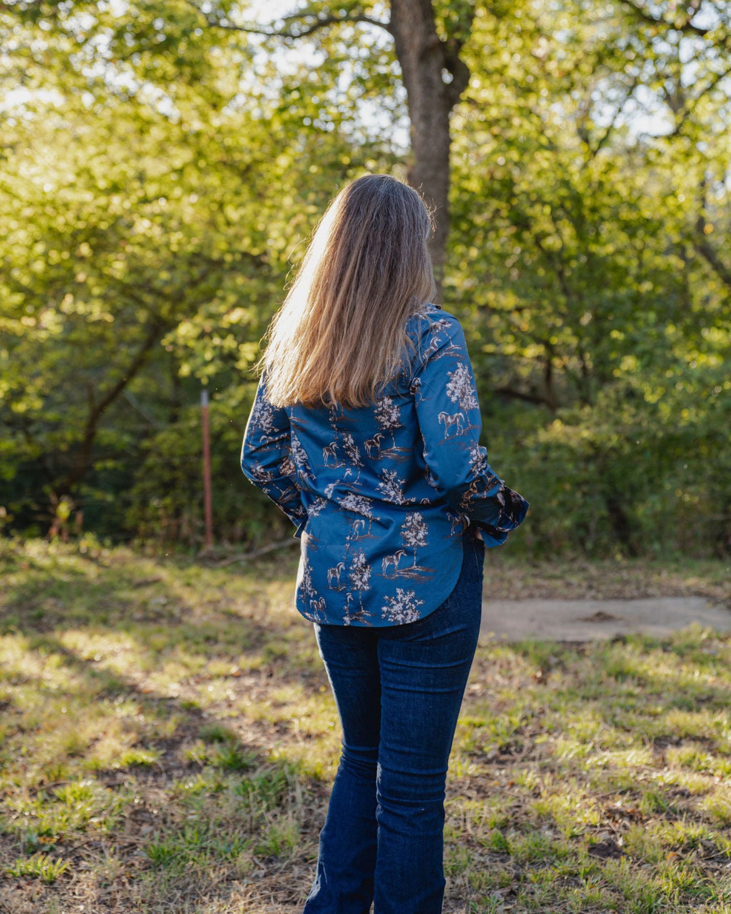 Person wearing a blue floral shirt standing in a forested area