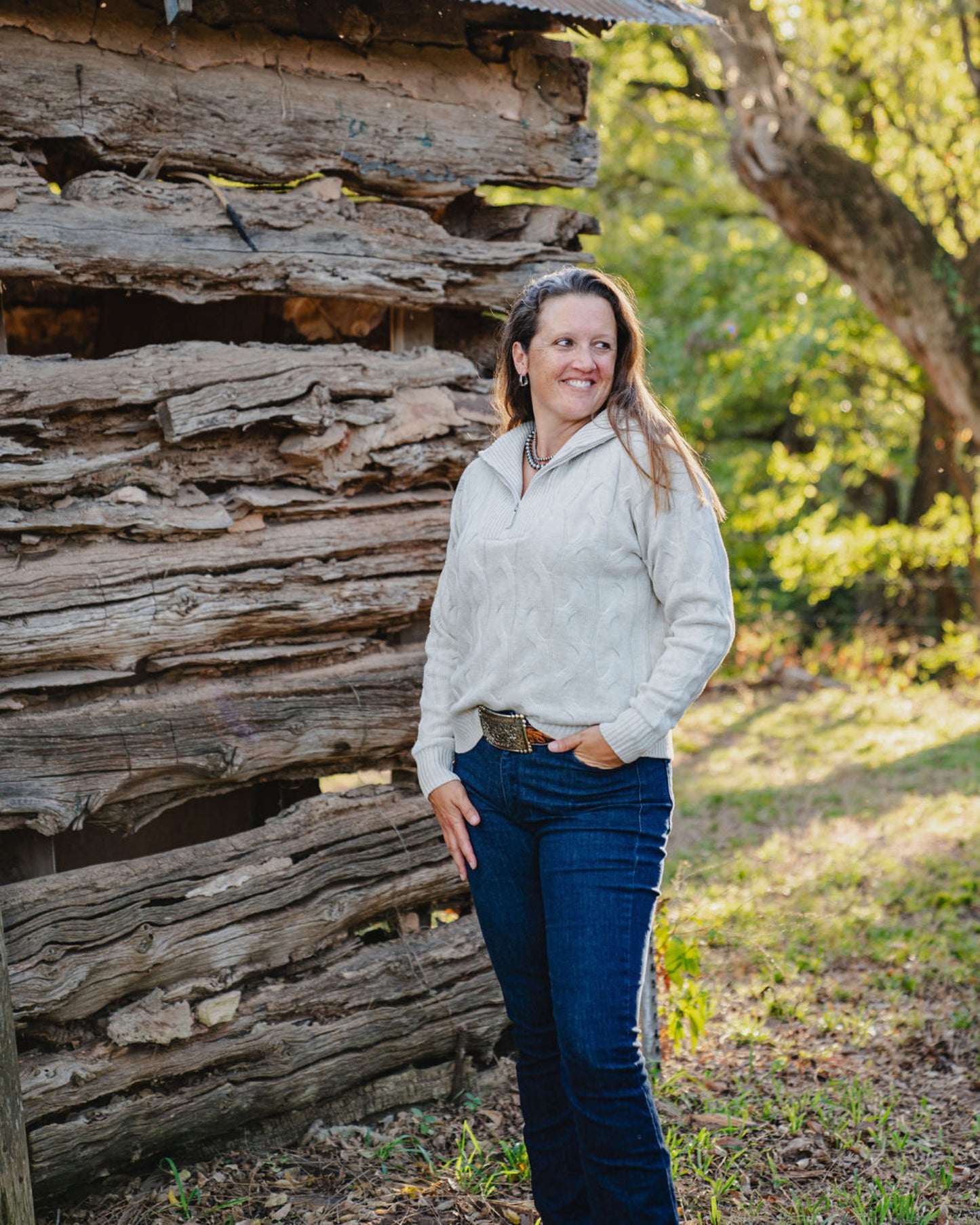 Woman standing in front of a rustic wooden cabin in a natural setting