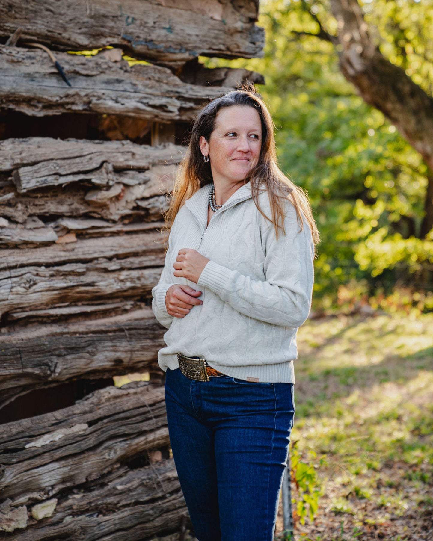 Woman standing in front of a wooden structure with trees in the background