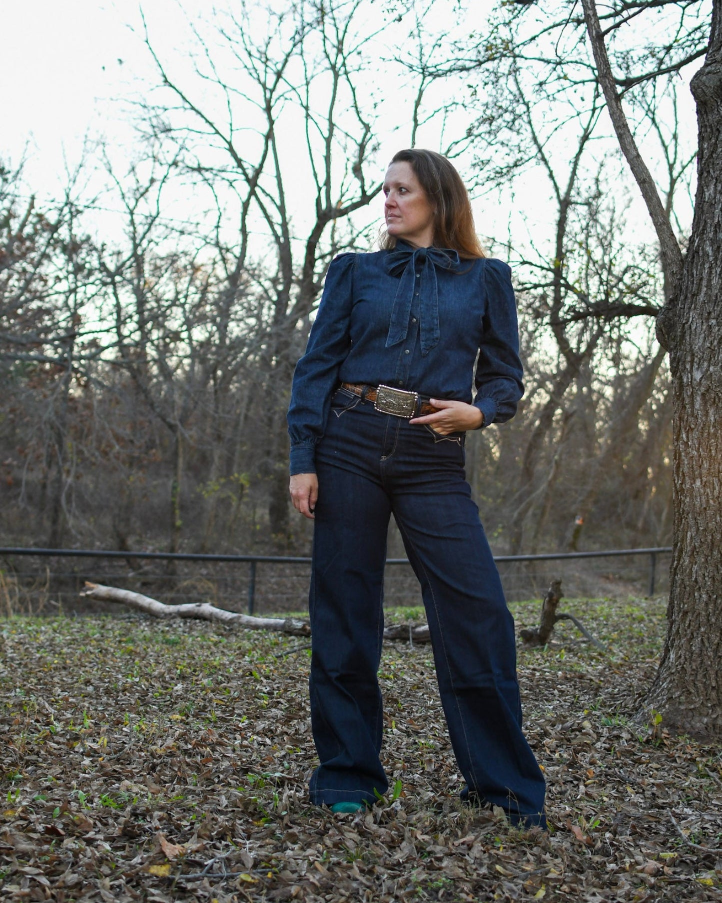 Model wearing a denim outfit standing by a tree