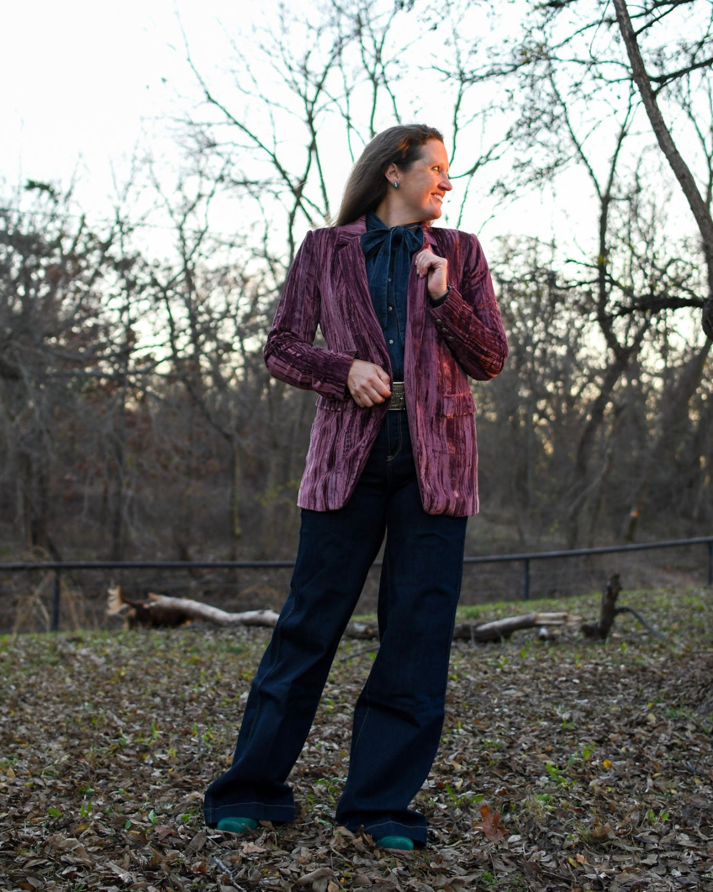 model wearing blazer and jeans standing outside with trees