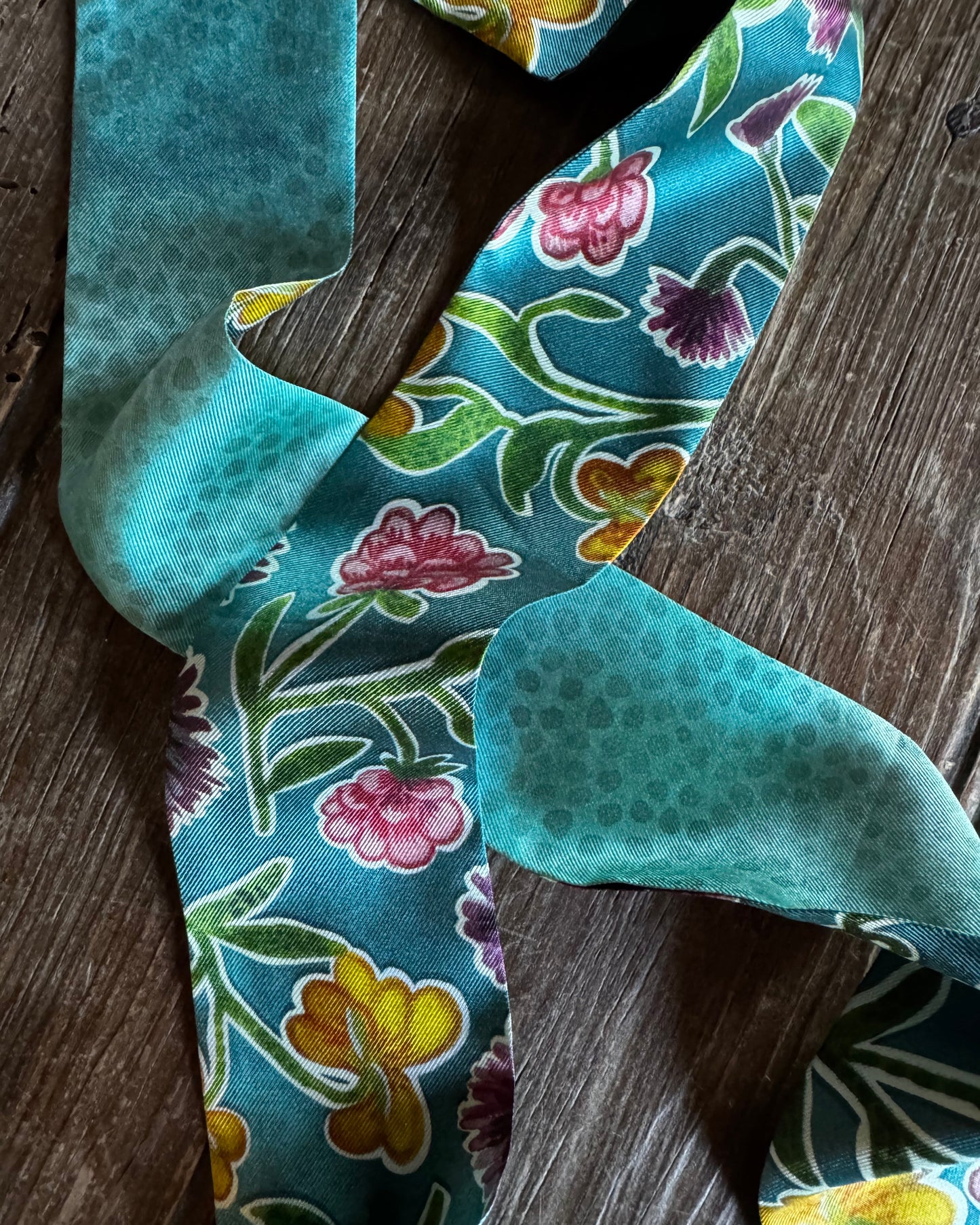 close up of teal ribbon scarf with floral design on wooden background