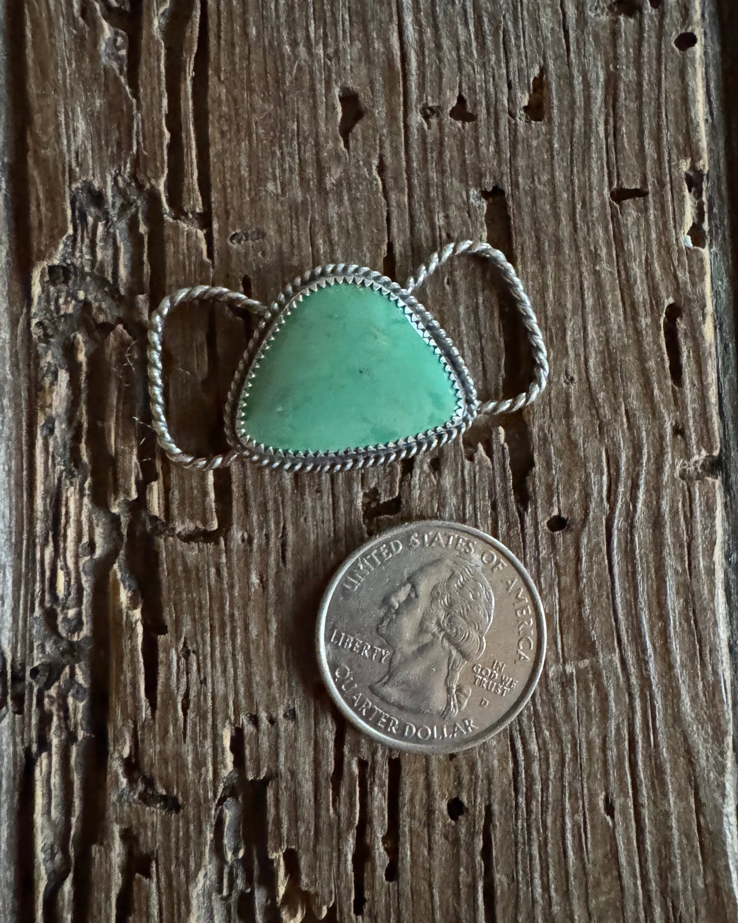 Turquoise twilly slide with silver band on a wooden surface next to a coin for scale.