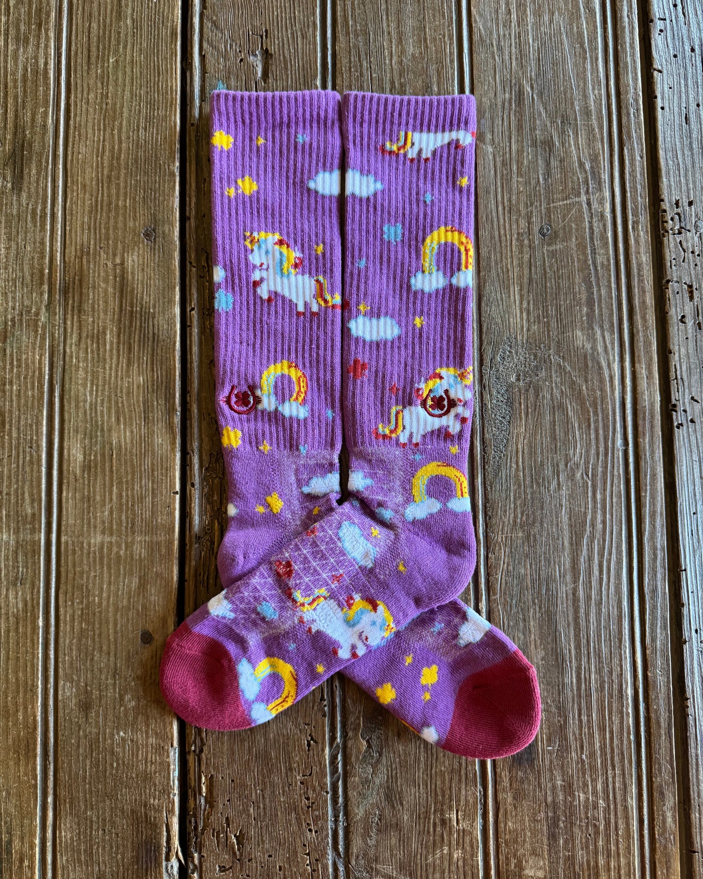Lucky Unicorns Performance Socks in purple showing design on rustic wood background