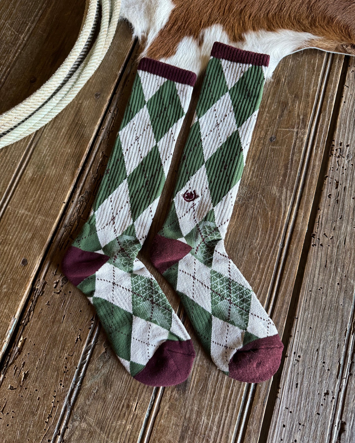 Green and white checkered socks with maroon accents on a wooden surface