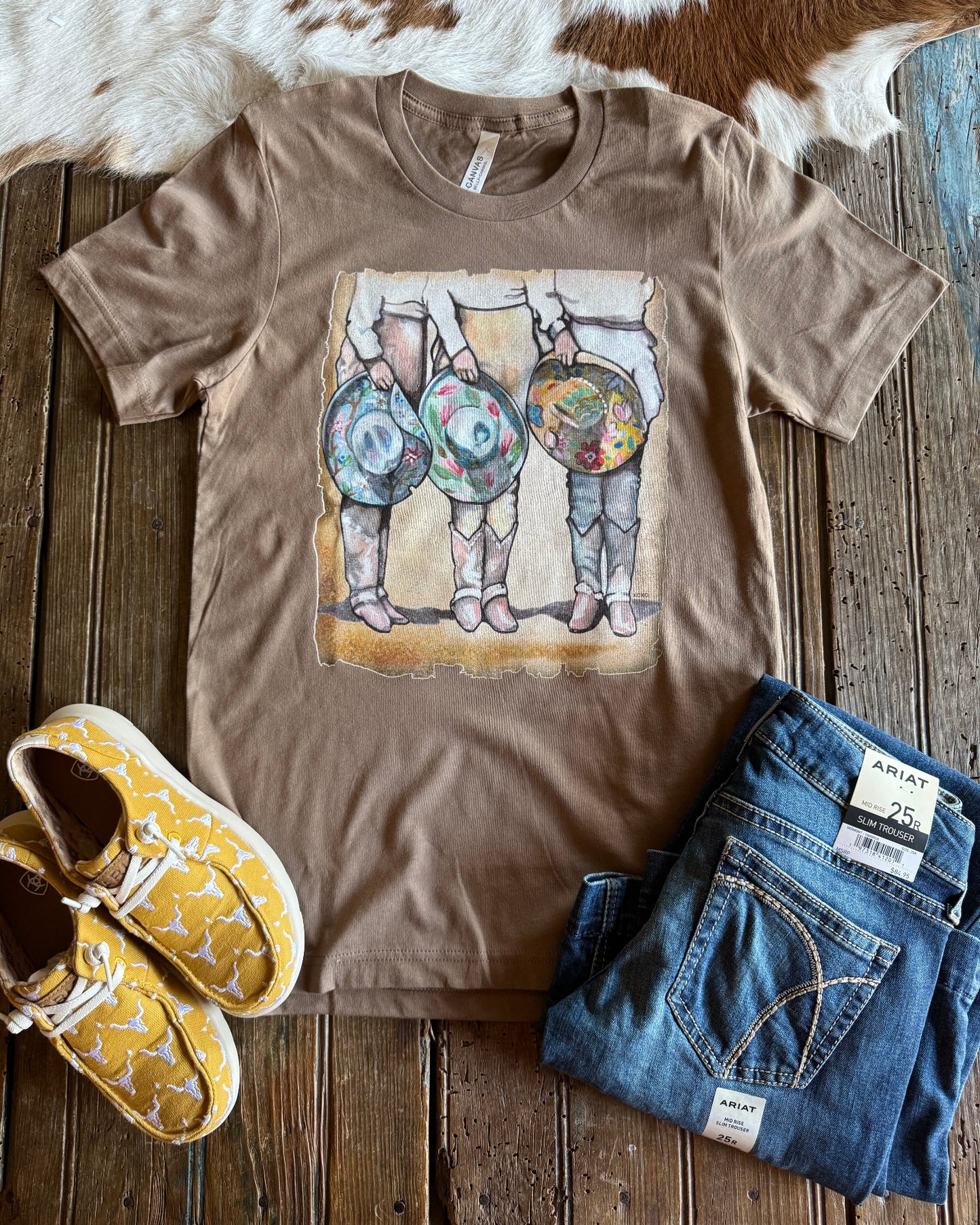 Cowgirls & Cowboy Hats graphic tee with shoes and jeans on rustic wood background