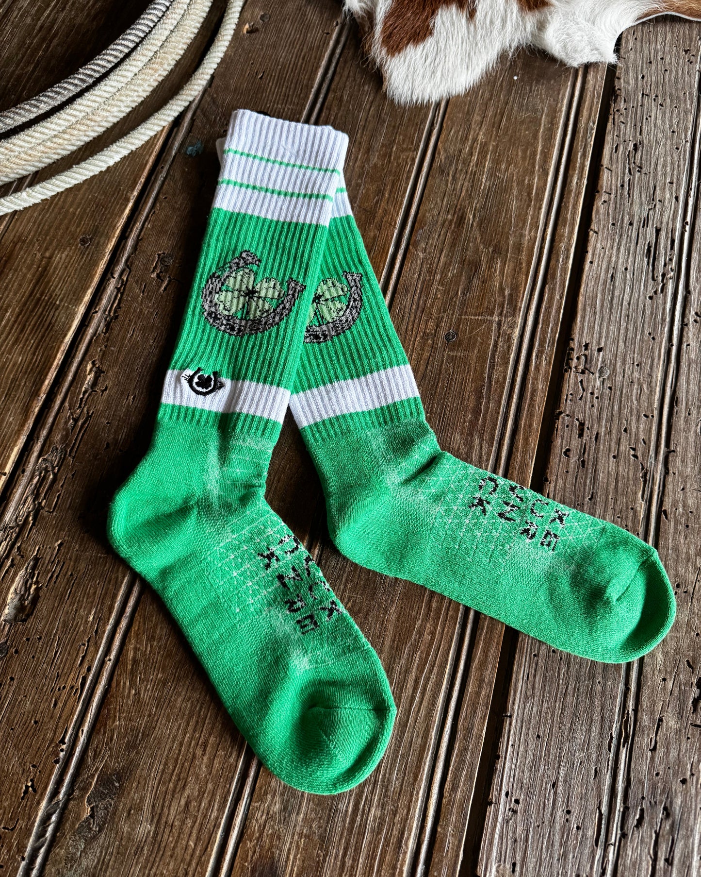 Green socks with white stripes on a wooden surface